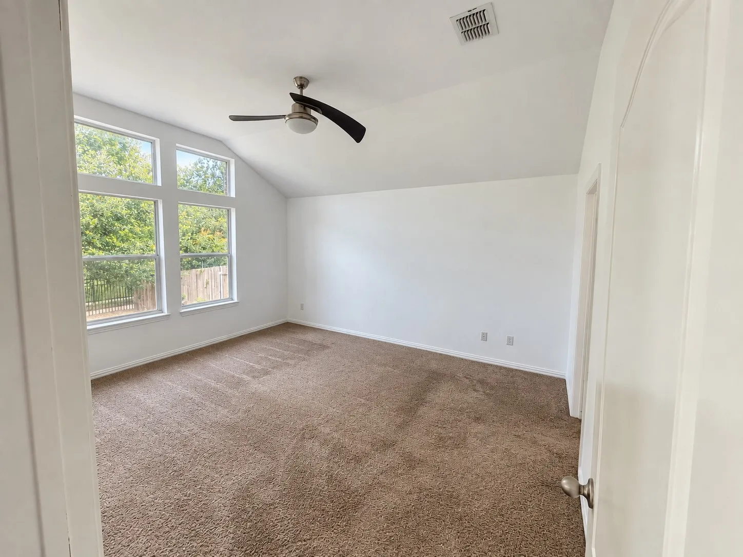 Vaulted ceilings, a contemporary ceiling fan, and abundant natural light from multiple windows