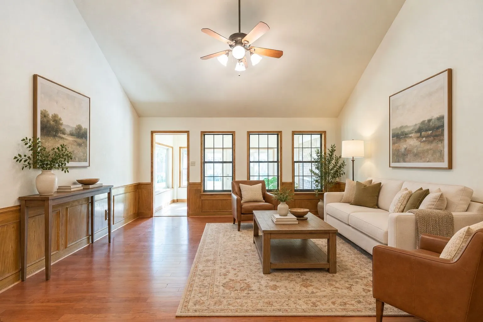 Vaulted ceiling, wood-finish flooring, wainscoting, multi-pane windows, and a ceiling fan