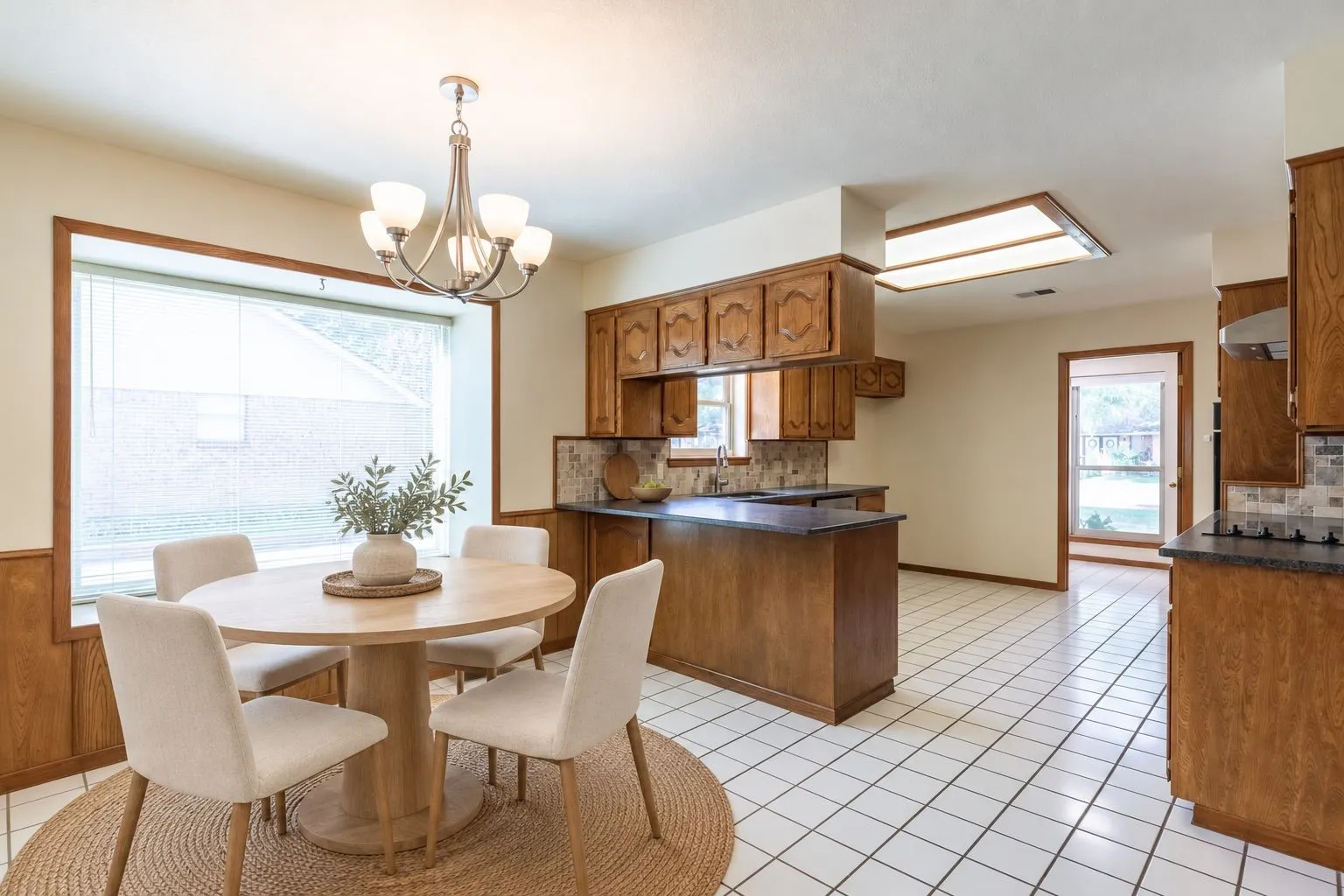 White square tile flooring, wood paneling, wood cabinetry, built-in lighting, and a large window