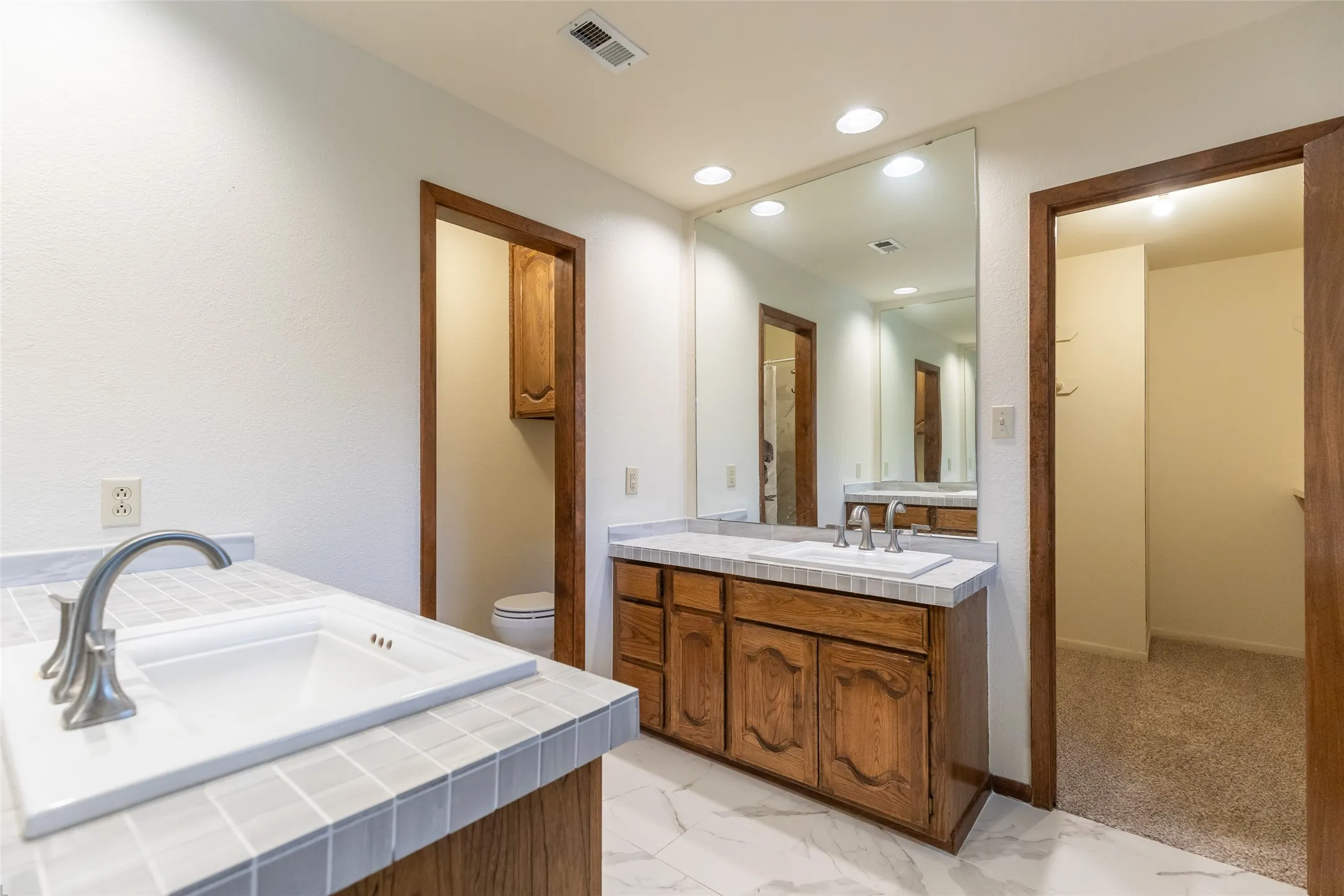 Dual vanity with wood-finish cabinetry and tiled countertops