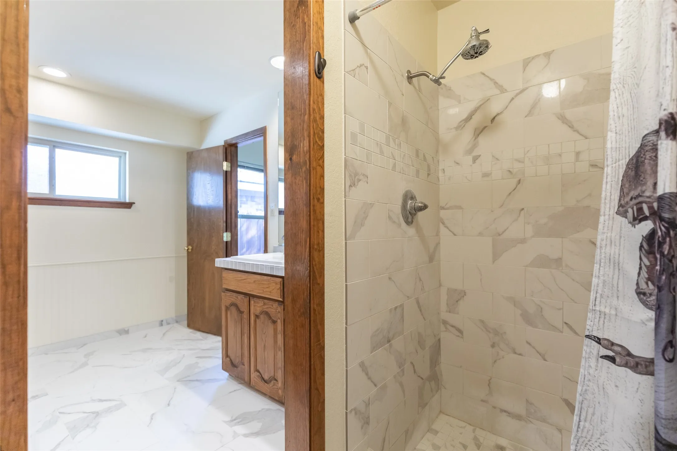 Tiled shower with a decorative mosaic band and a multi-setting shower head