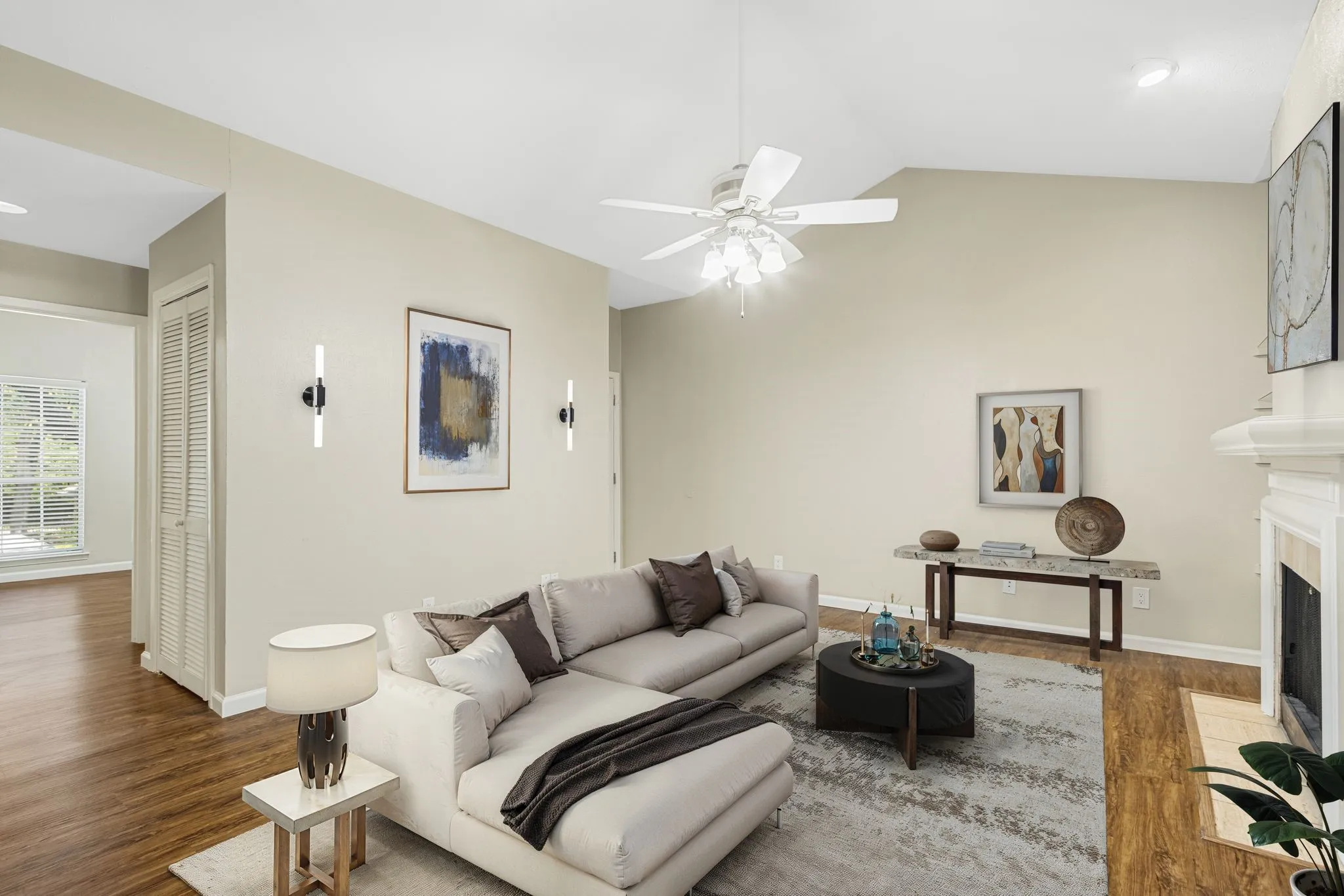 Living area featuring wood finished floors, vaulted ceiling, ceiling fan, and a tile fireplace