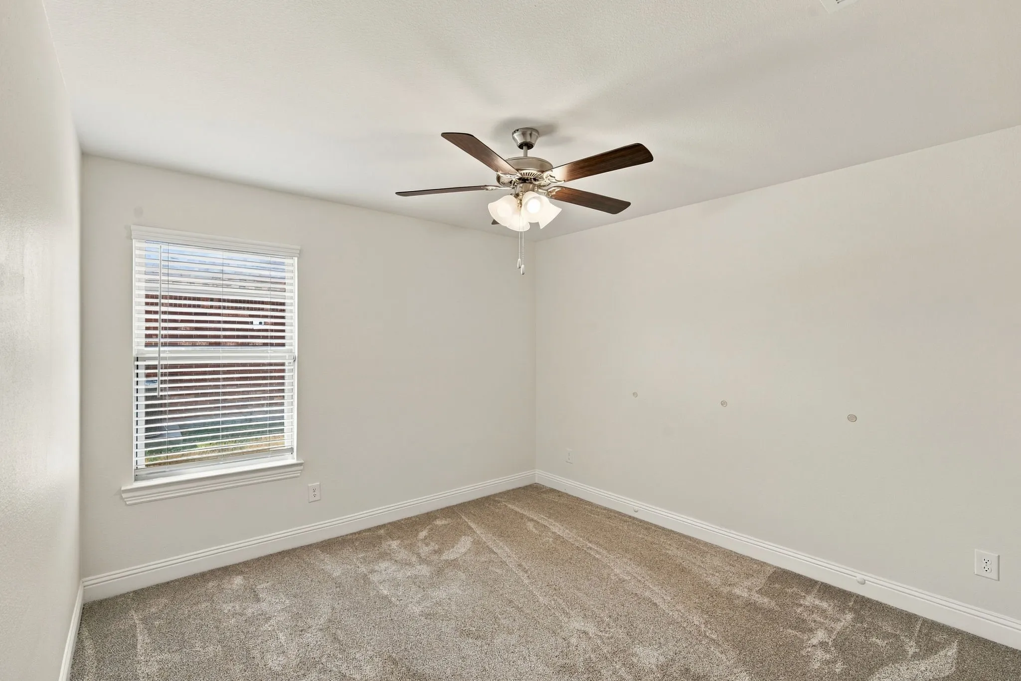 Recessed window with white blinds, neutral carpeting, and a ceiling fan with integrated lighting