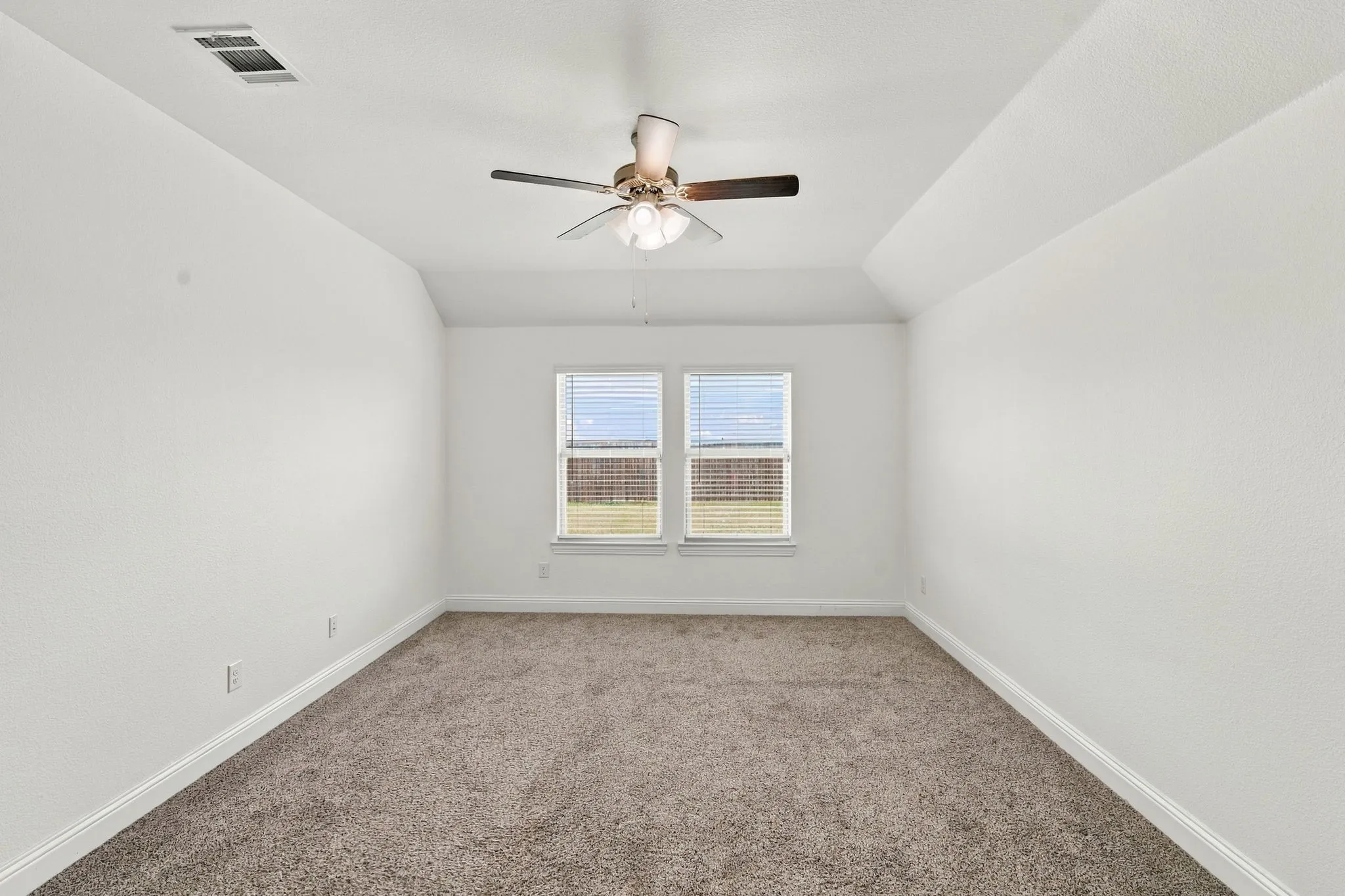 Tray ceiling, flush-mount ceiling fan, dual windows with blinds, neutral-tone carpeting, and white wall finishes