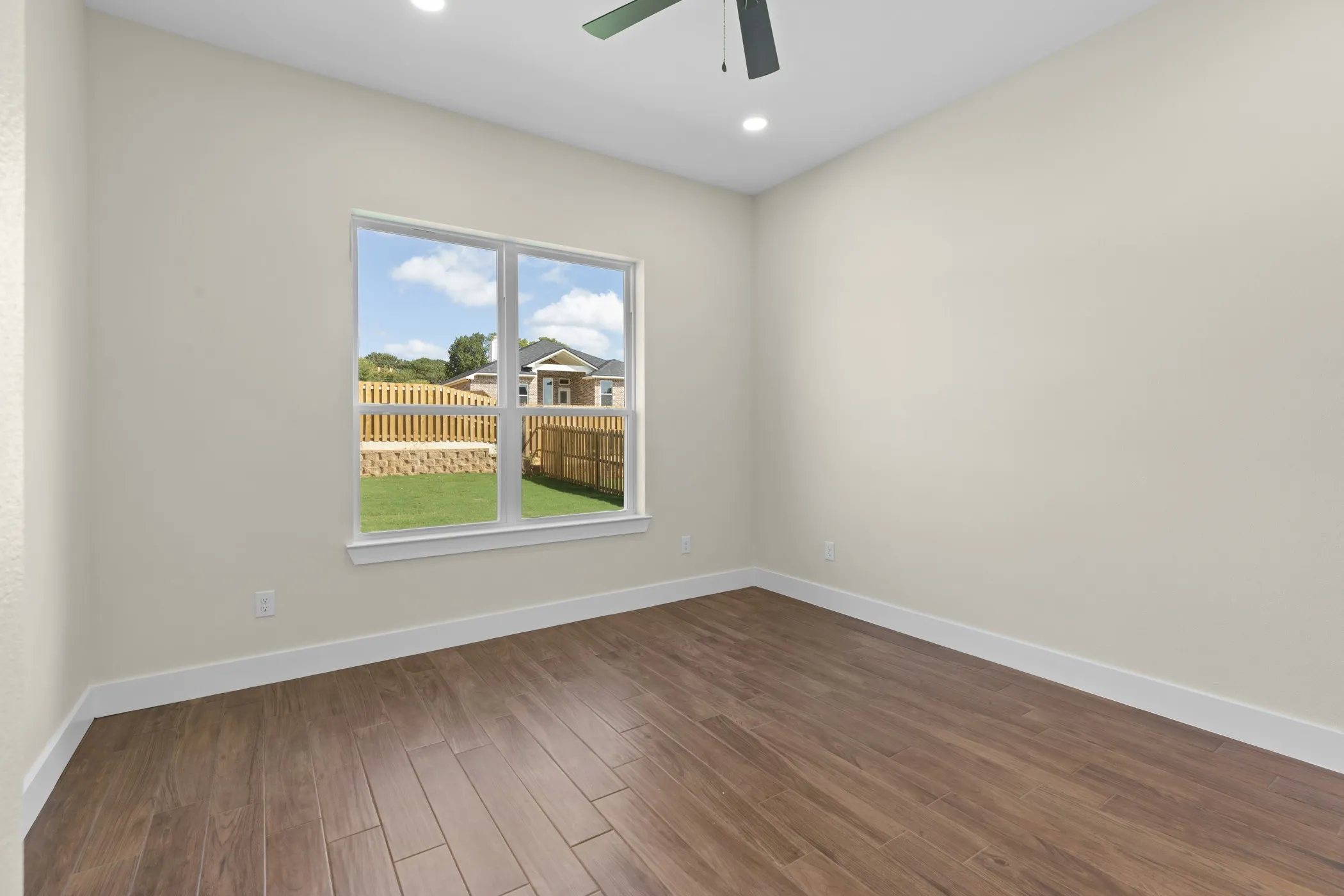 Hardwood-finish flooring, recessed lighting, ceiling fan, and a large window