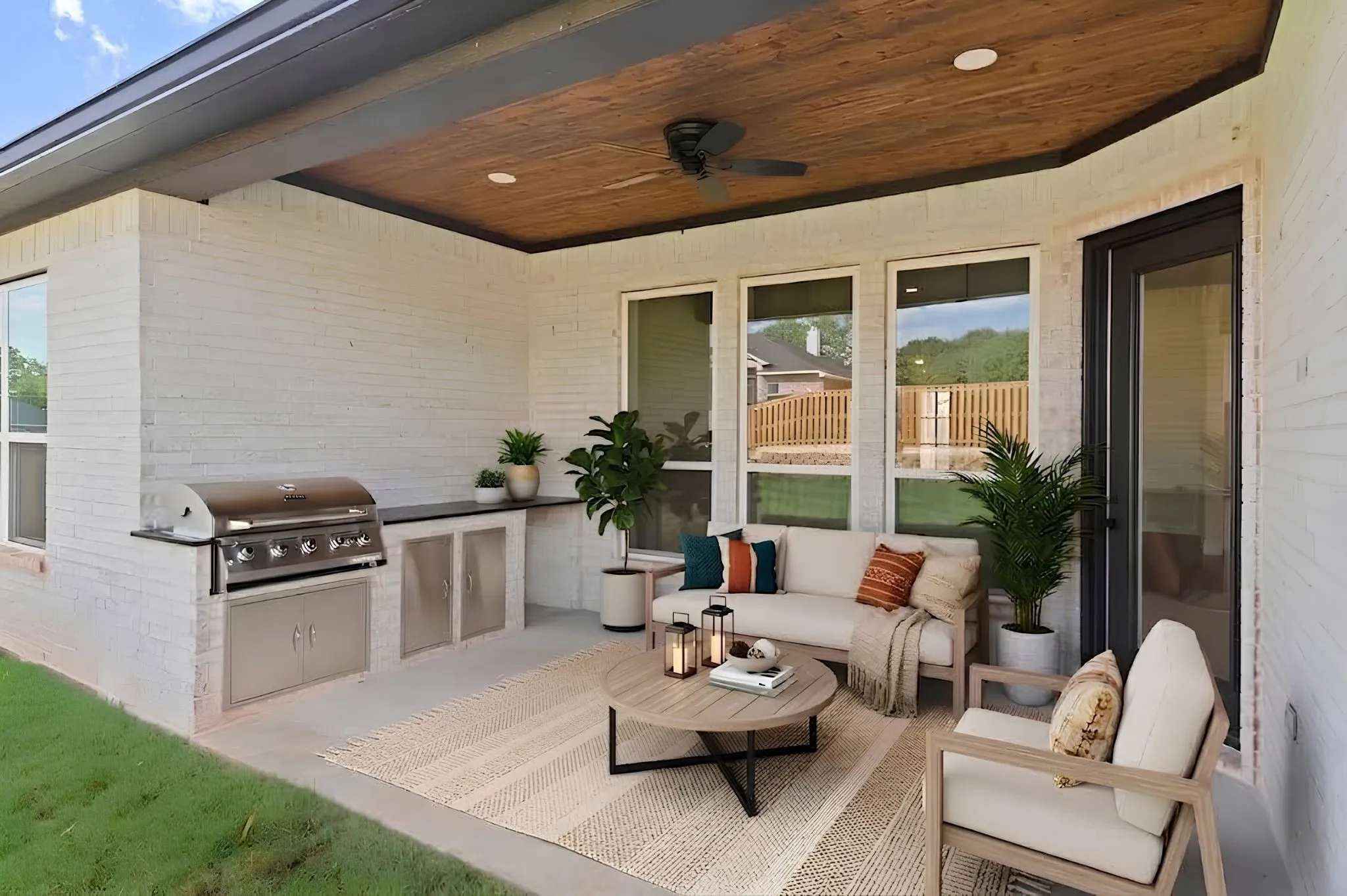 Covered outdoor living space featuring a built-in grill, integrated cabinetry, and wood-finish ceiling with a ceiling fan