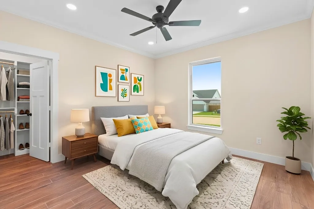 Warm neutral wall tones, wood-finish flooring, white window trim, and a ceiling fan with integrated lighting