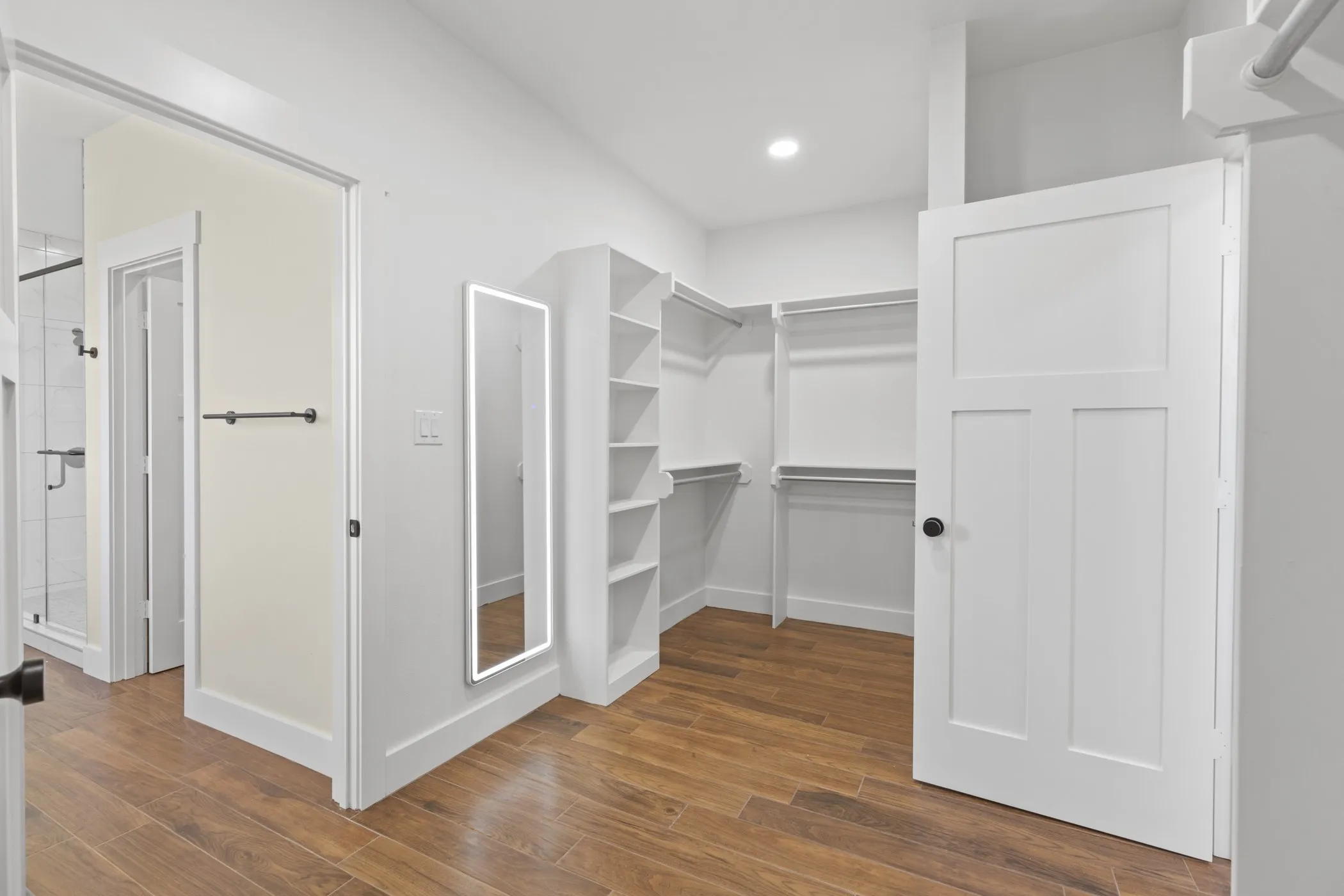 Walk-in closet with wood-finish flooring, built-in shelving, and integrated hanging rods