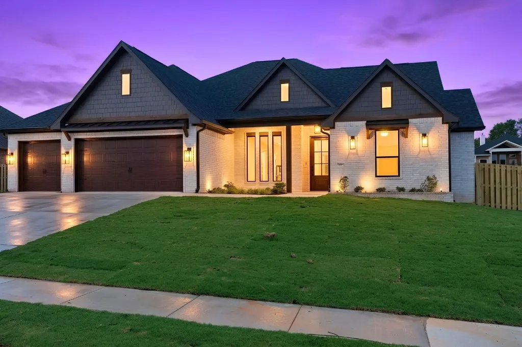 Brick exterior with dark shake siding accents, multiple gables, a three-car garage, and a wood privacy fence