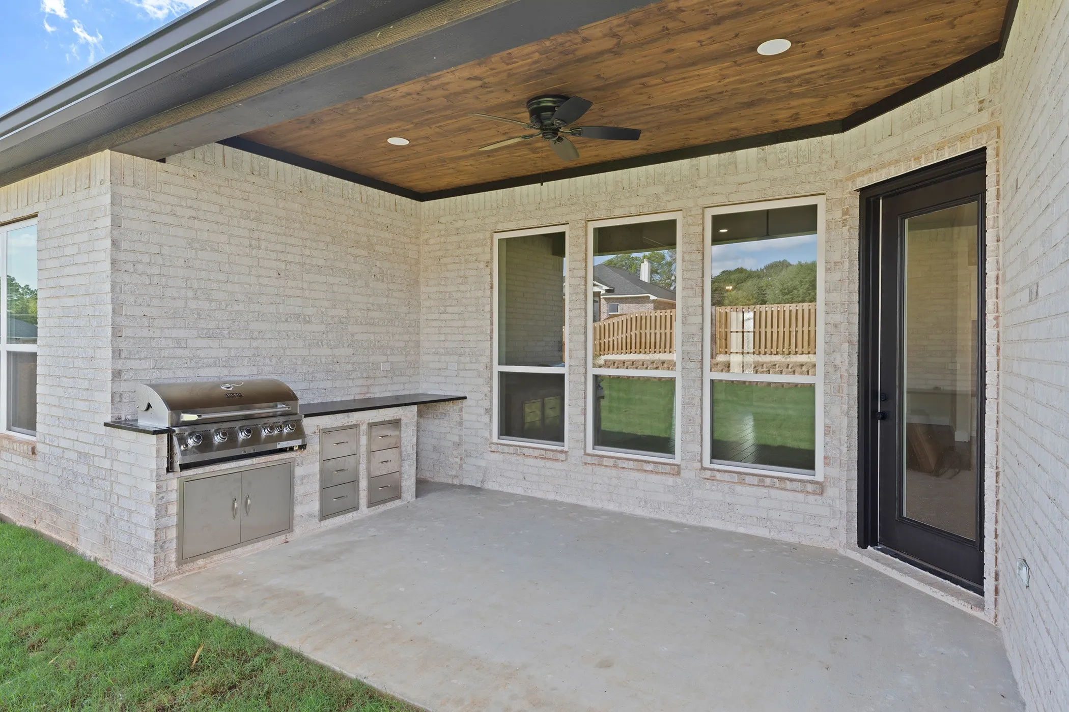 Covered patio featuring an outdoor kitchen with built-in grill and stainless steel drawers, a wood-finish ceiling, and ceiling fan