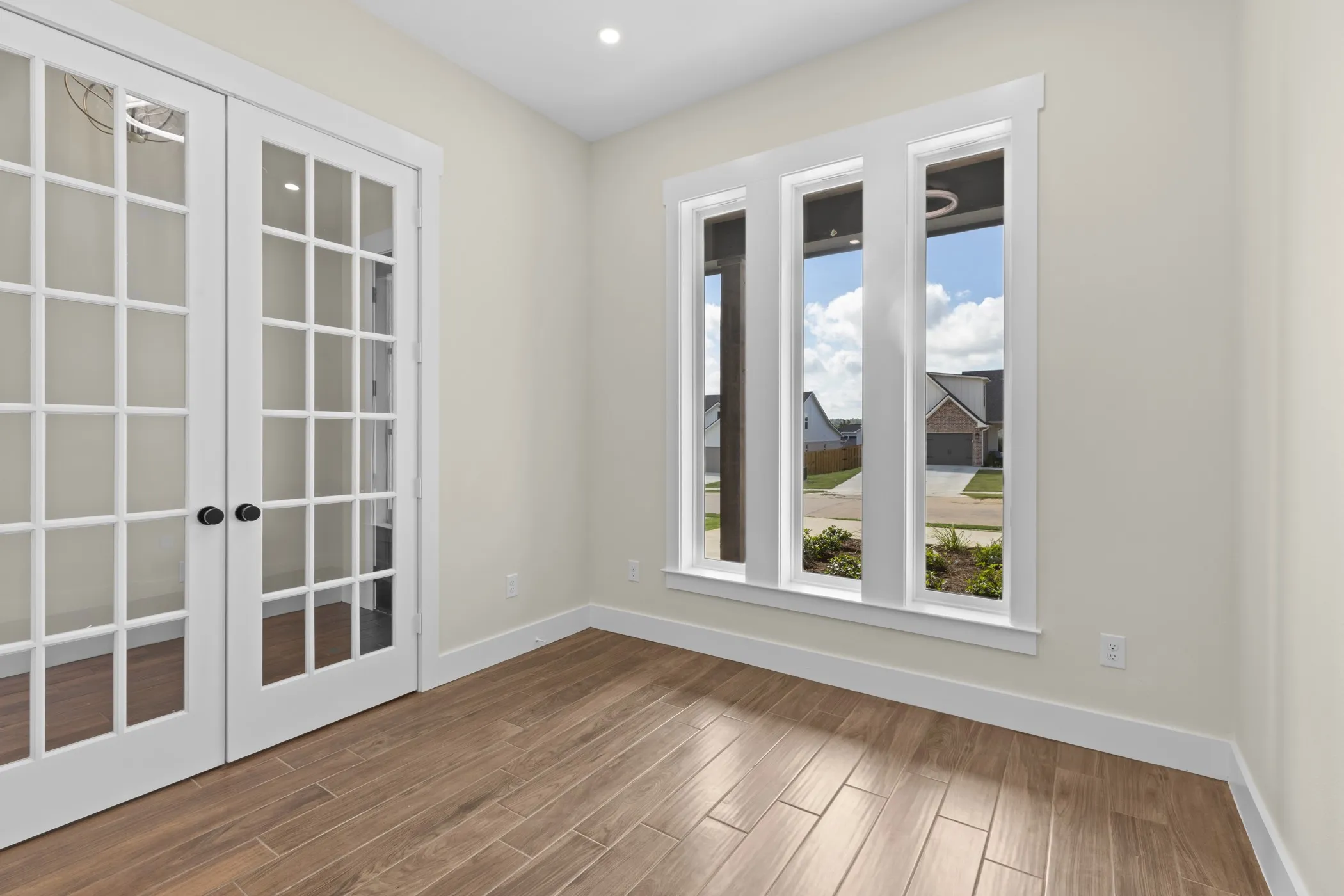 French doors with grid paneling, wood-finish flooring, recessed lighting, and three vertical windows with white trim