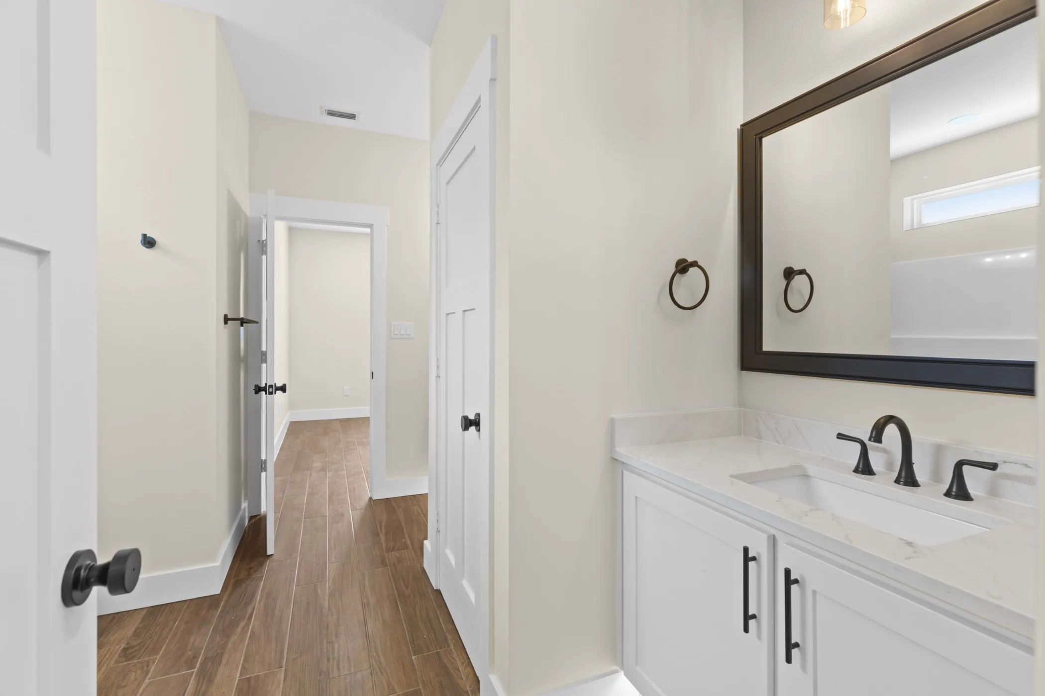 Vanity with white shaker-style cabinetry, quartz countertop, integrated sink, and matte black hardware
