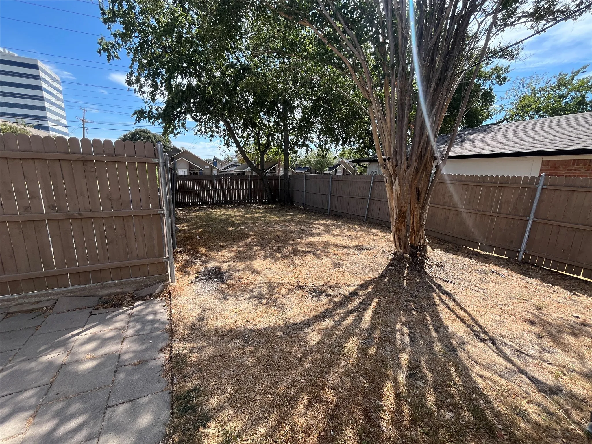 Fully fenced backyard with a mature tree and a stone paver path