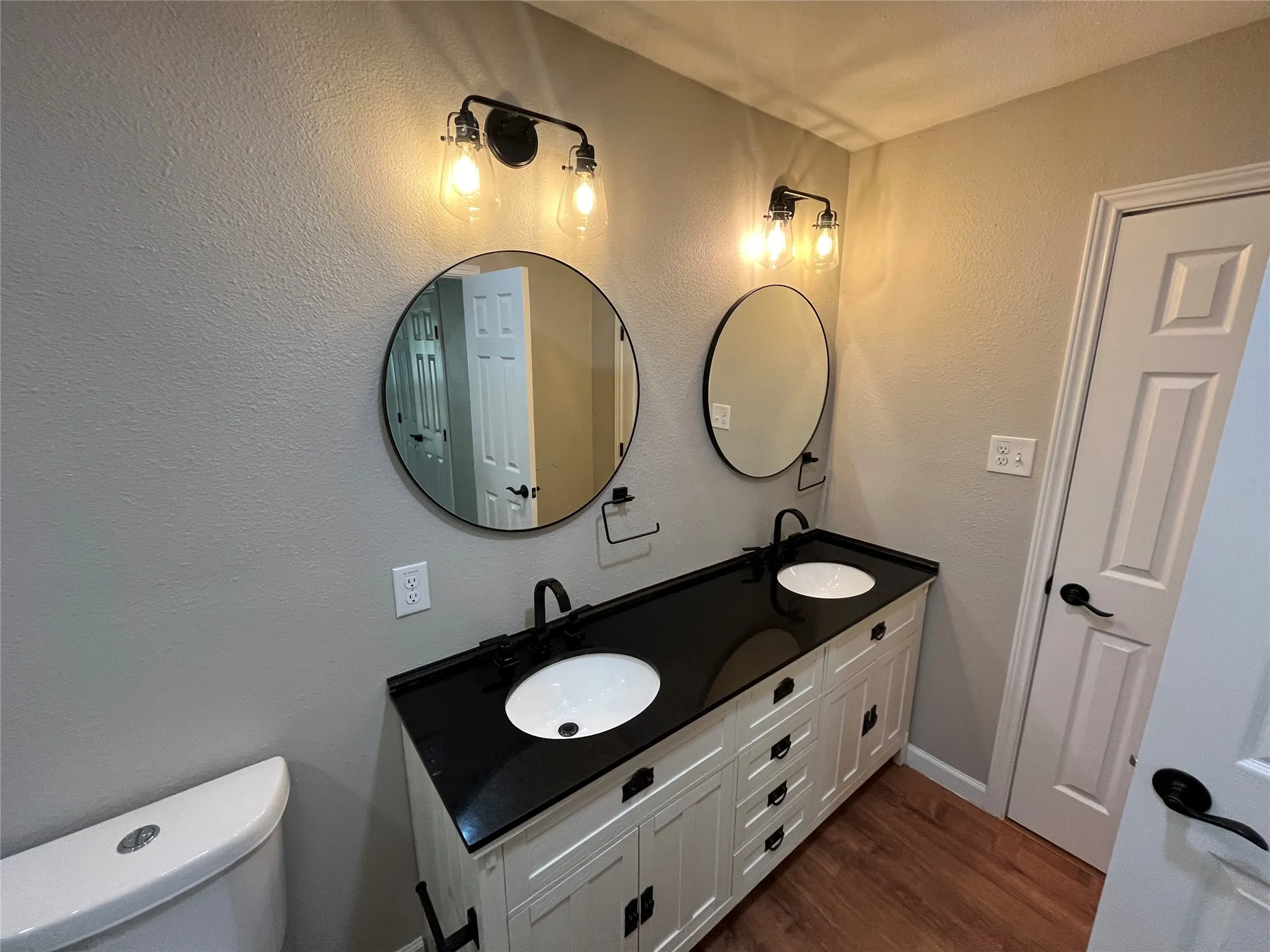 Double vanity with white cabinetry, black countertop, and dual vessel sinks