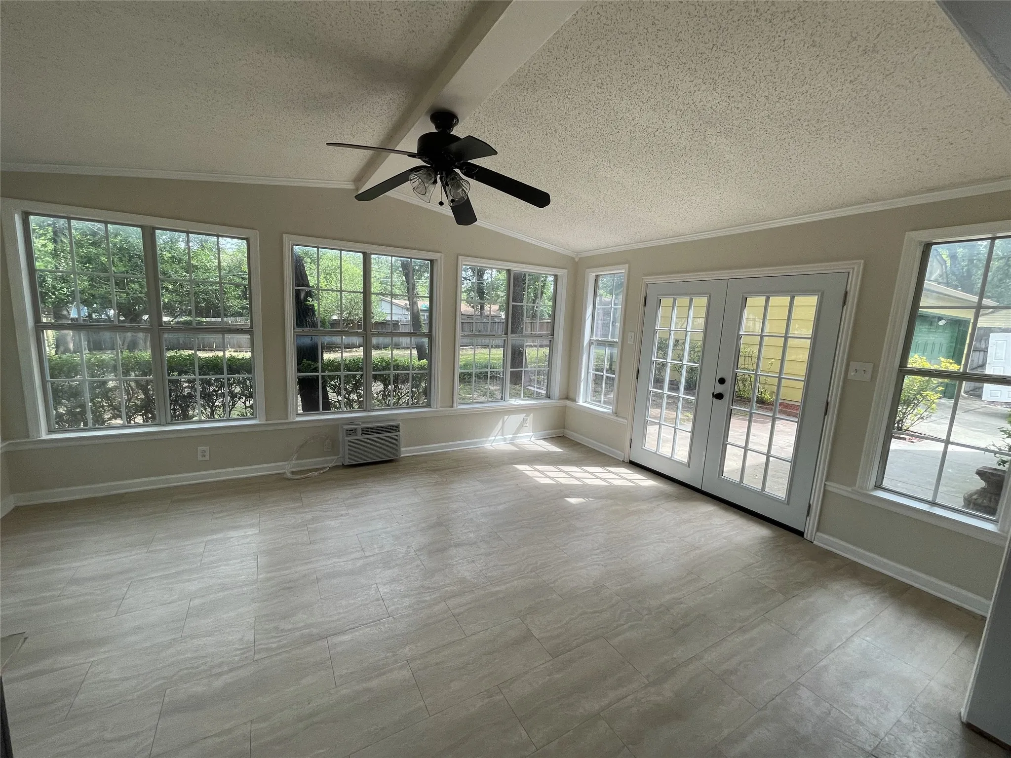Sunroom with abundant windows, French doors, wood-finish flooring, and a ceiling fan