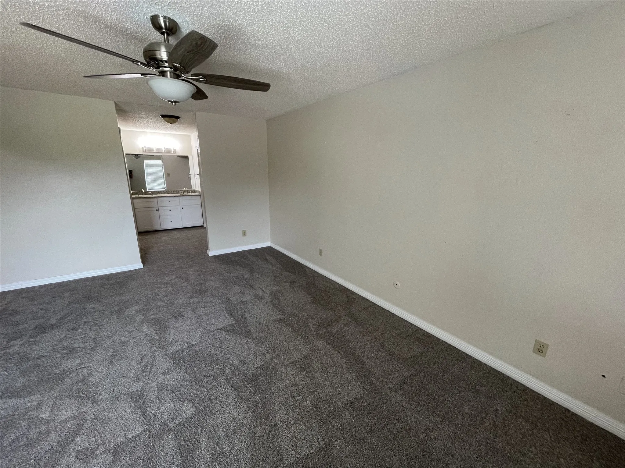 Textured gray carpeting with light-toned walls and a ceiling fan with integrated lighting