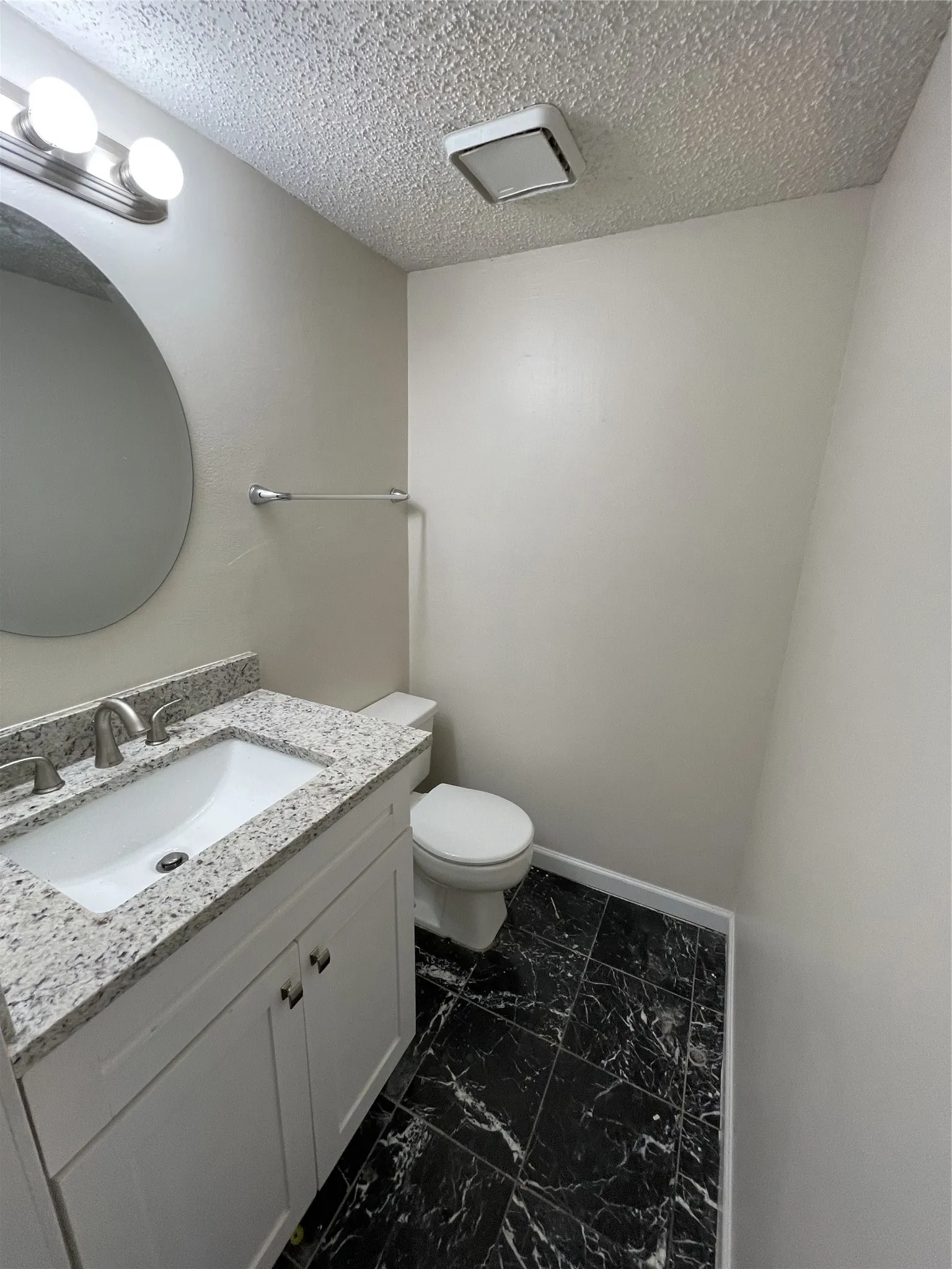 Vanity with a granite countertop, undermount sink, and brushed nickel faucet