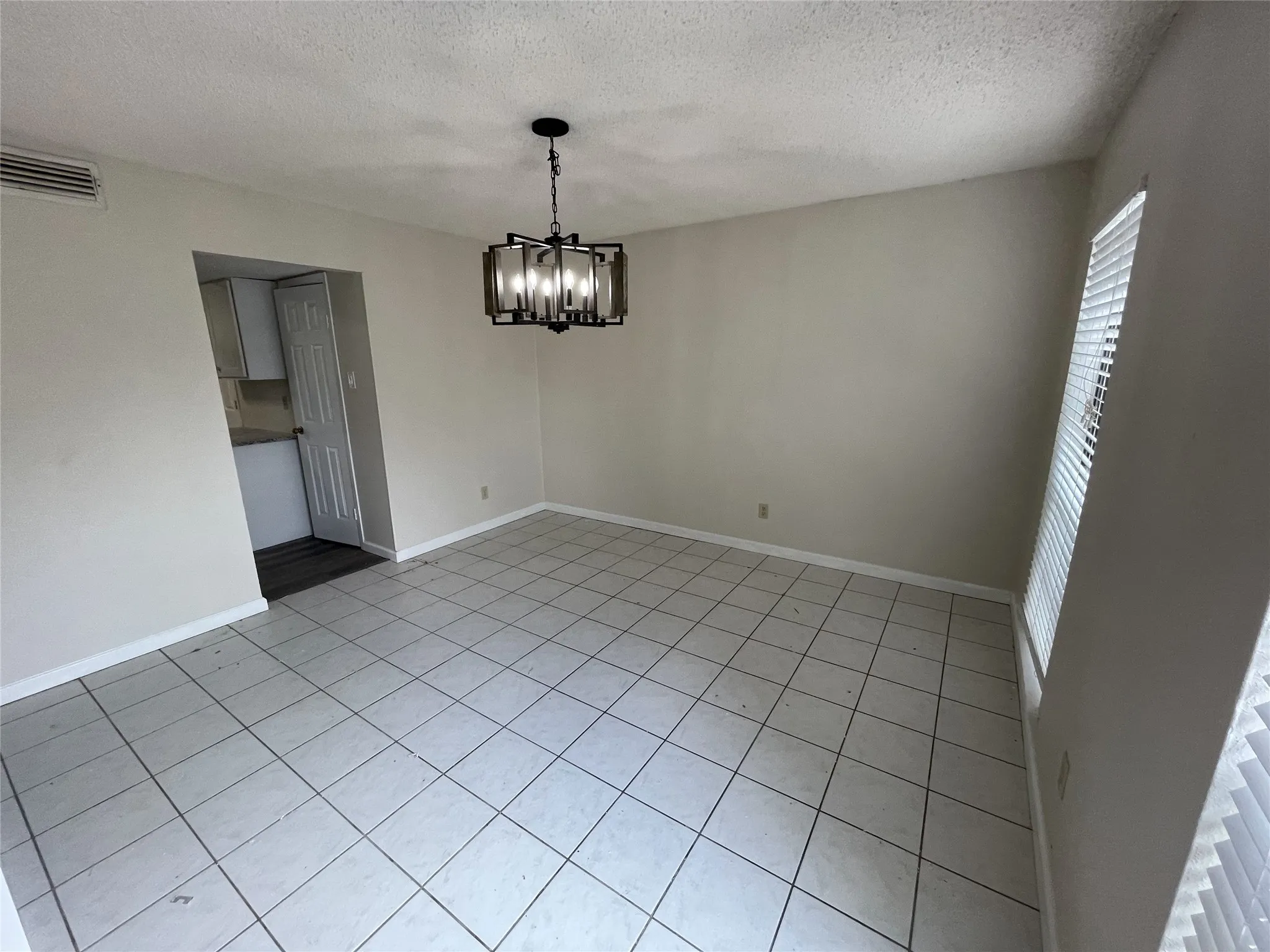 Neutral wall paint, tile flooring, and a modern chandelier