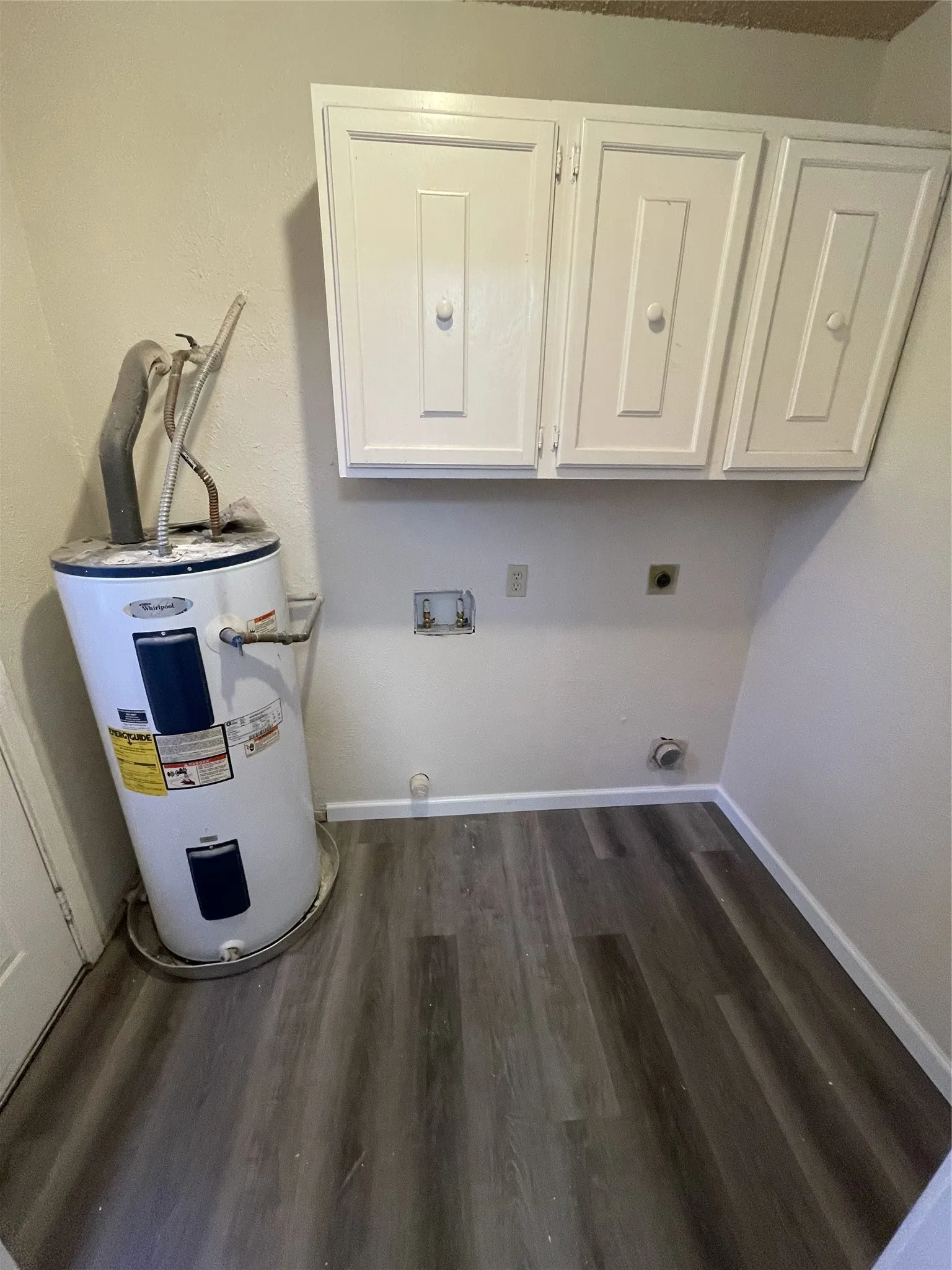 New wood-finish flooring with white baseboards, and white upper cabinetry