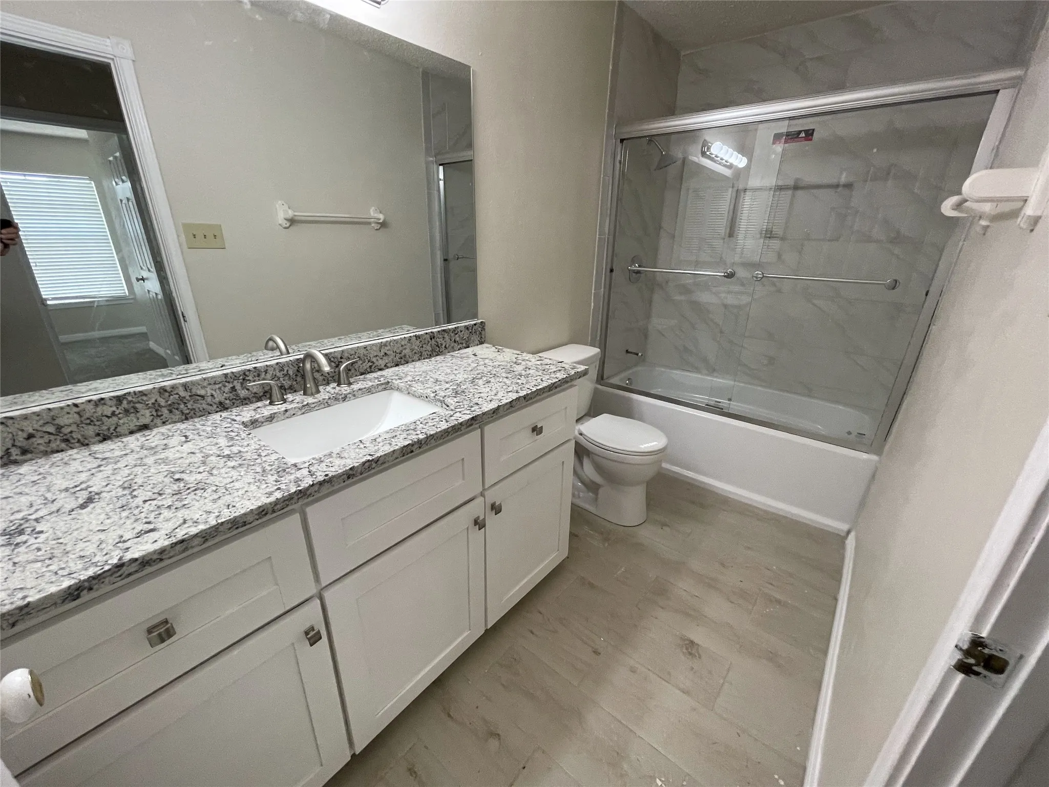 White shaker-style vanity with a speckled countertop and undermount sink