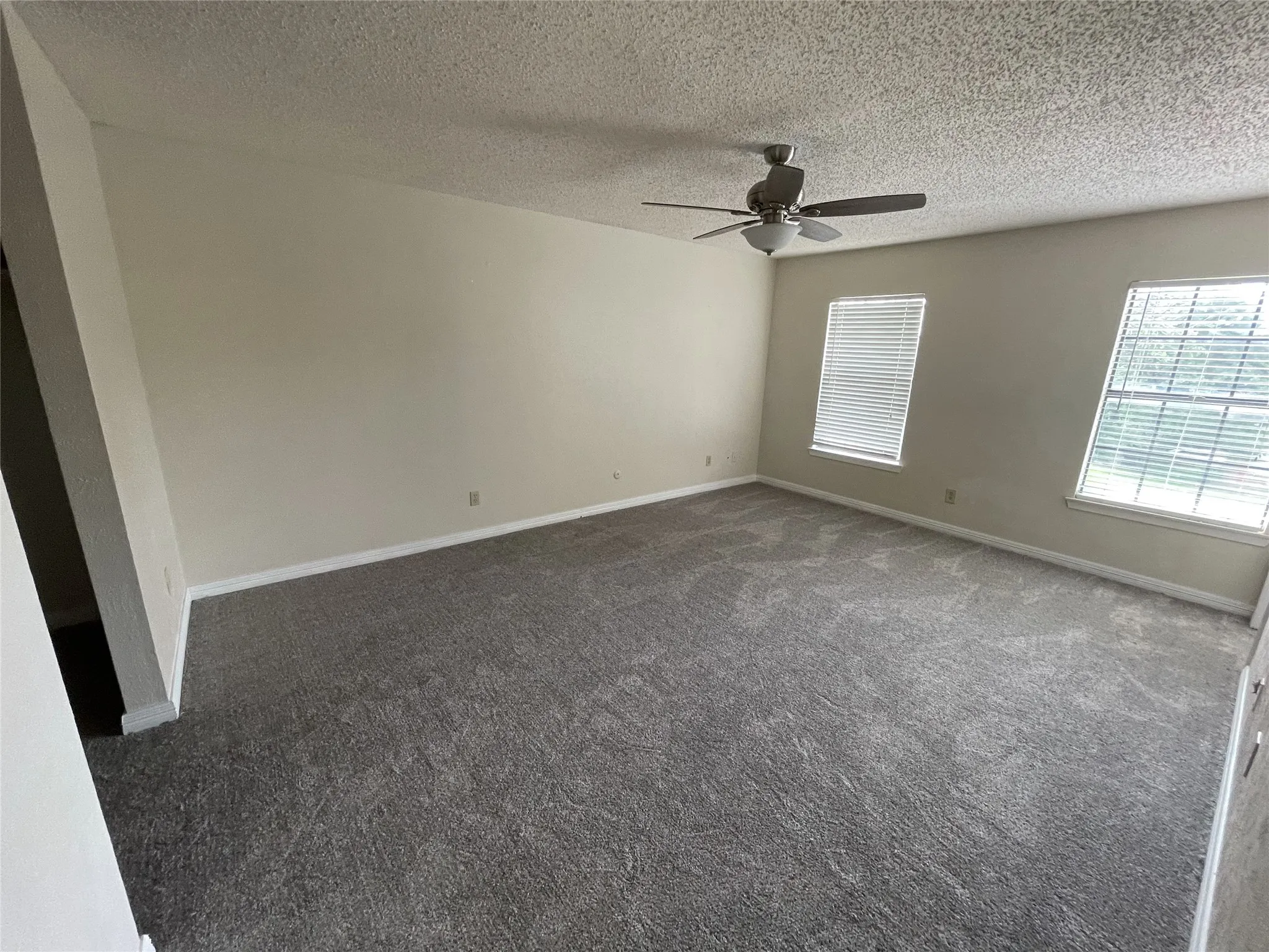 Recessed lighting, ceiling fan, two windows with blinds, and neutral-toned carpeting