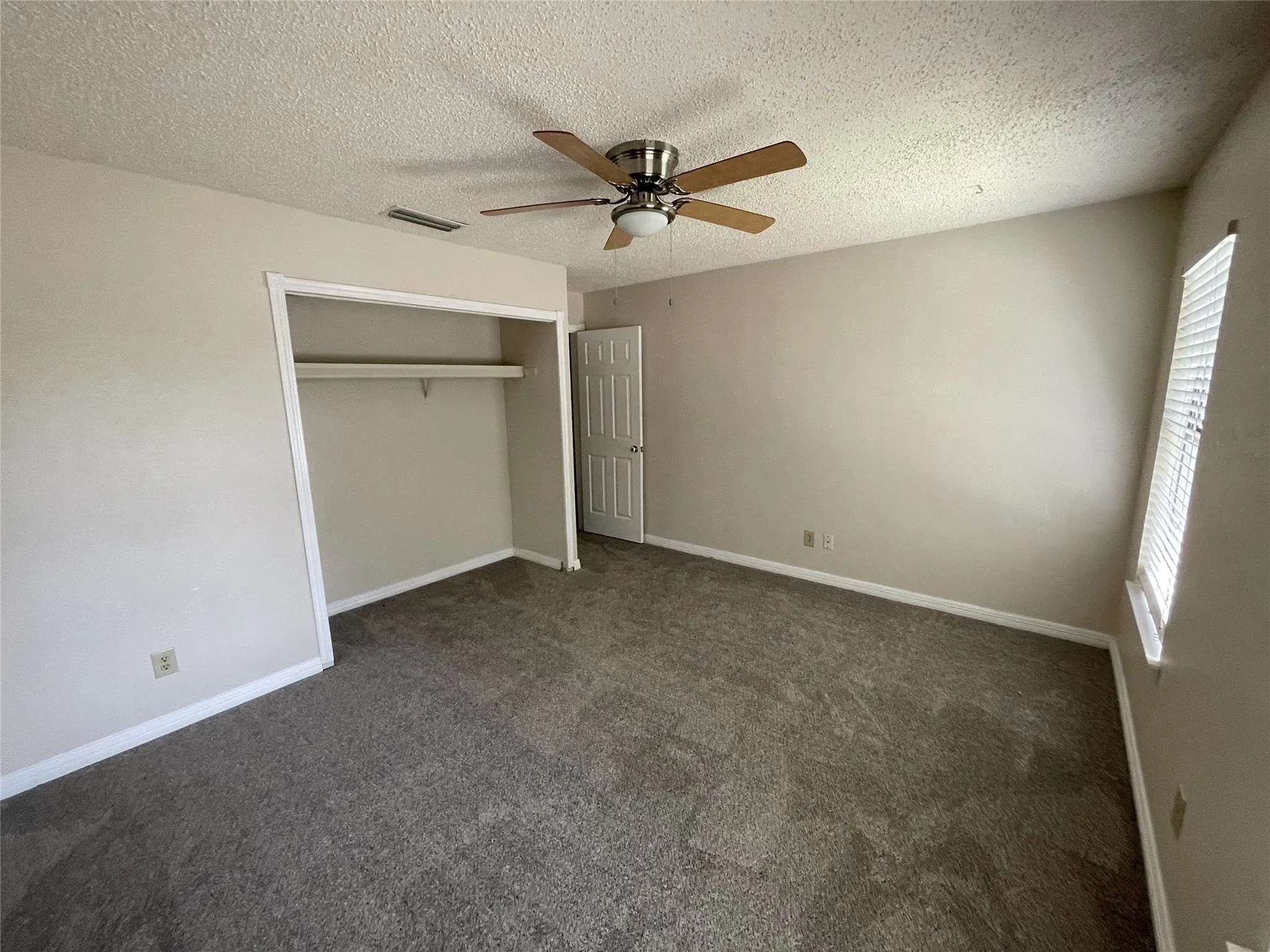 Carpeted interior with neutral wall tones and a ceiling fan