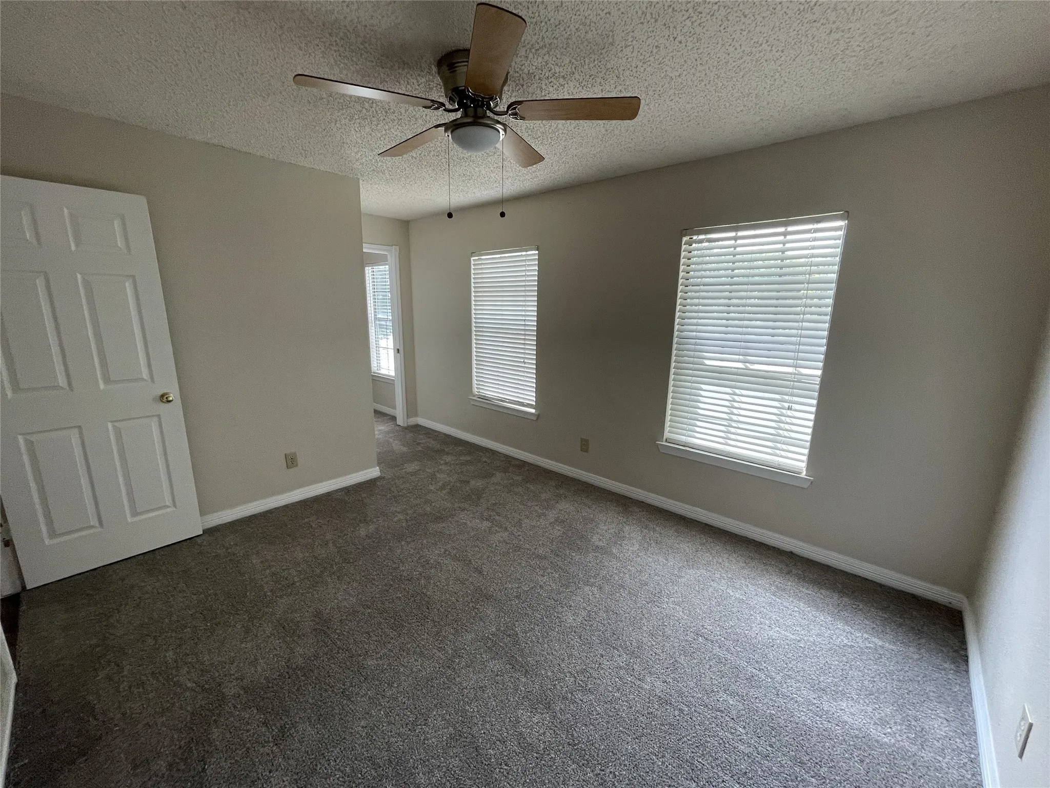 Wall-to-wall carpeting, ceiling fan with integrated lighting, two windows with blinds, and painted walls