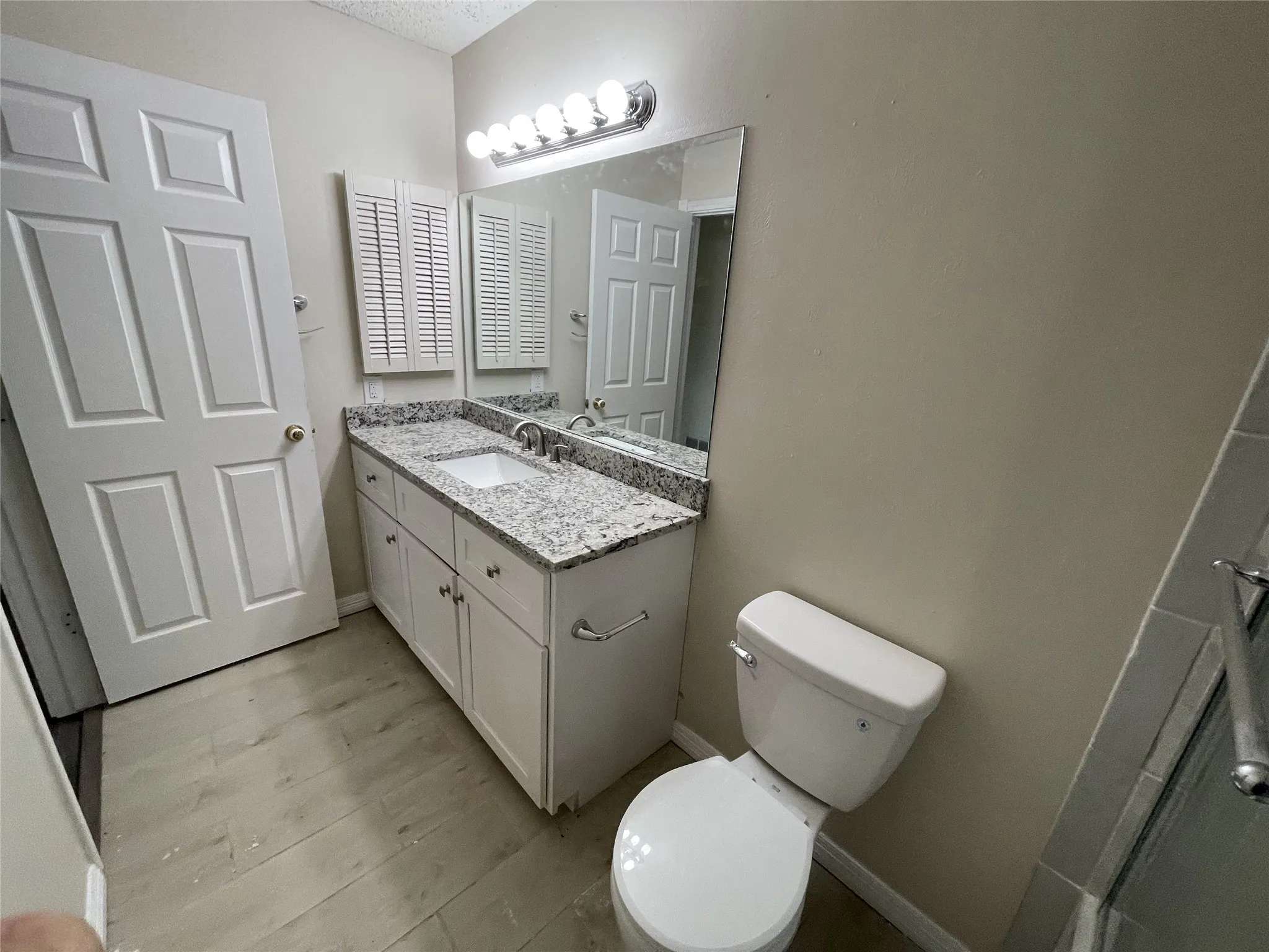 White vanity with a granite-style countertop, single basin sink, and a chrome faucet
