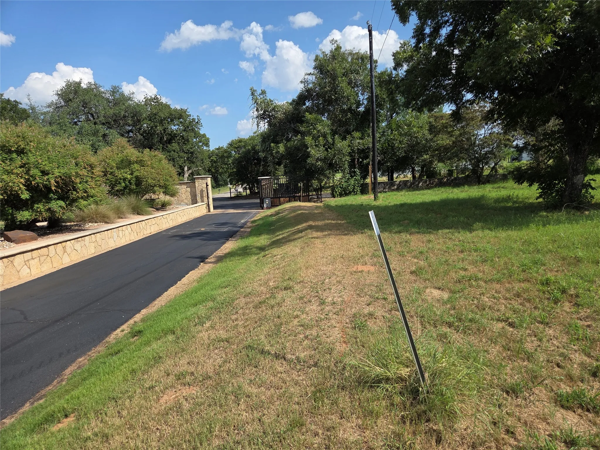 Orchards Blvd, stone retaining wall, and mature trees