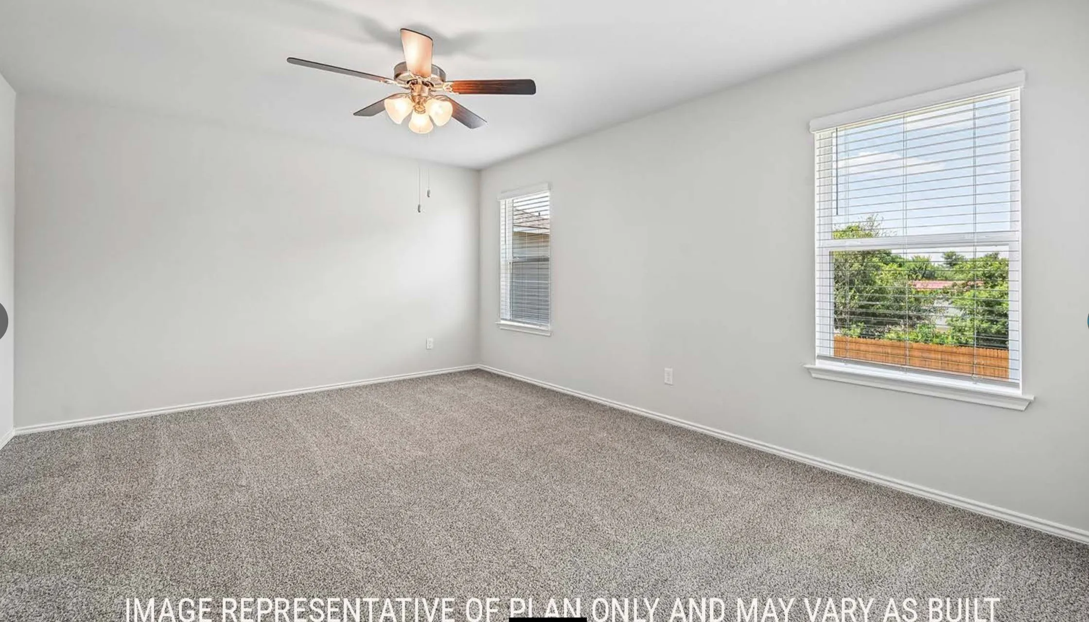 Spacious room featuring carpeting, multiple windows with blinds, and a ceiling fan