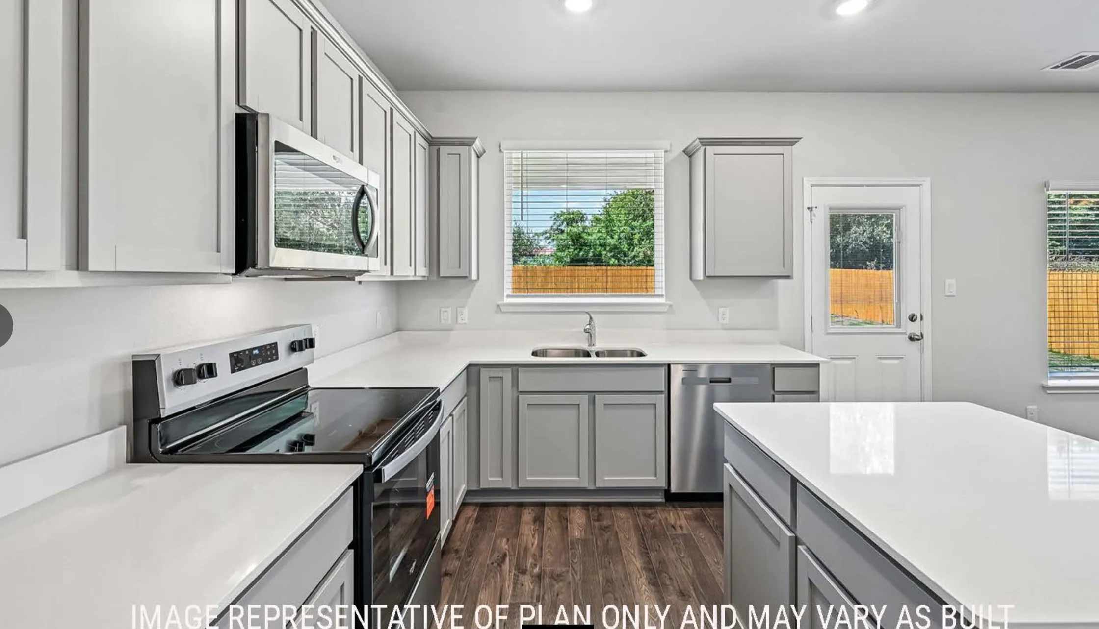 U-shaped kitchen with light gray cabinetry, white countertops, built-in stainless steel microwave, and wood-finish flooring