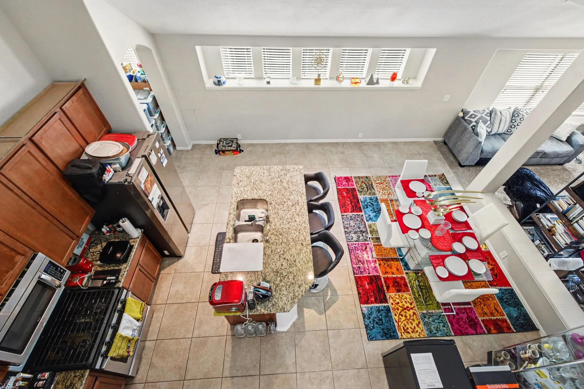 Kitchen featuring wood cabinetry, stainless steel appliances, and a granite-finish island with integrated sink