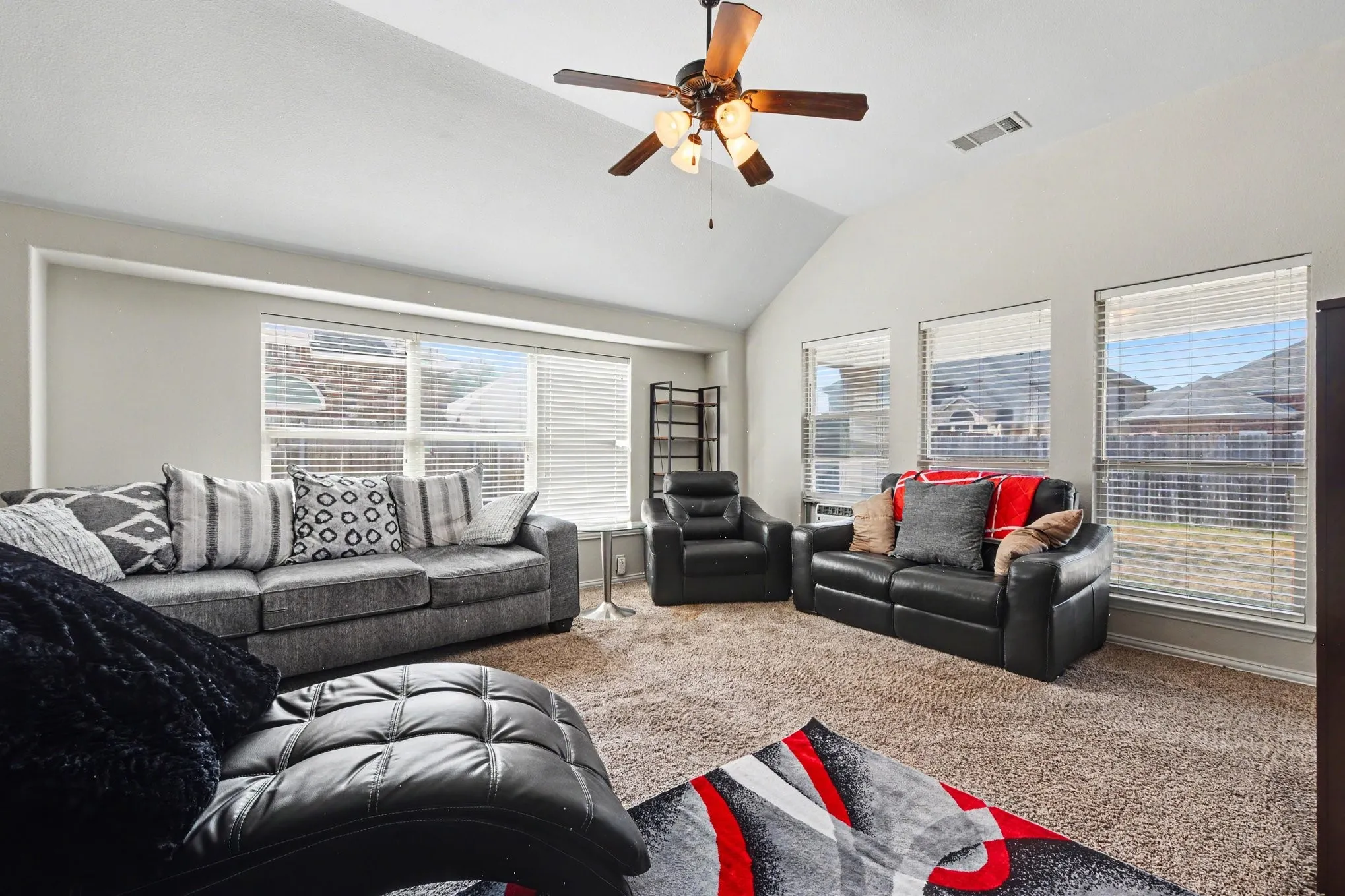 Vaulted ceiling with a ceiling fan, multiple windows with blinds, and neutral-toned wall paint