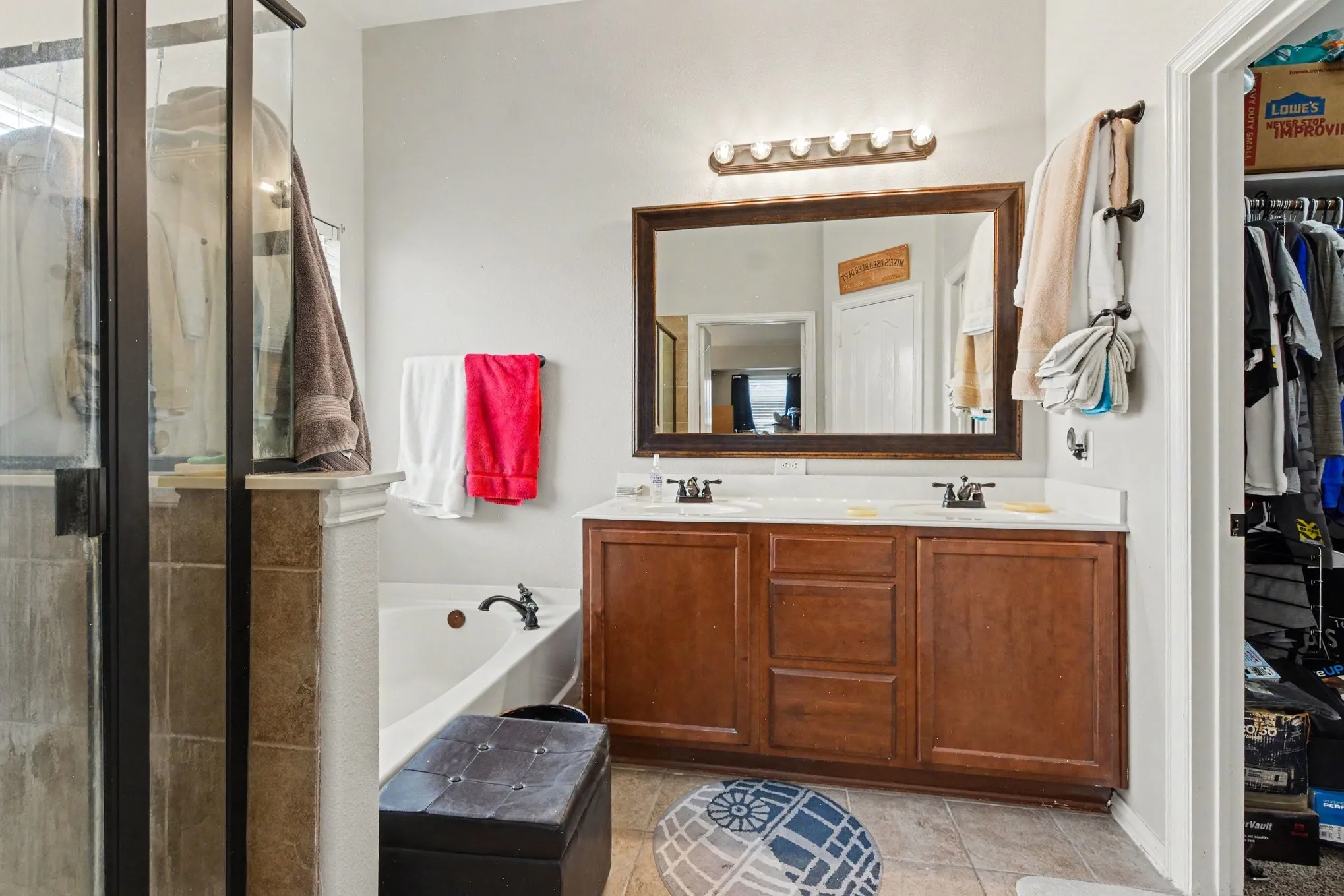 Master- Double vanity with wood-finish cabinetry, a large framed mirror, and a five-light fixture