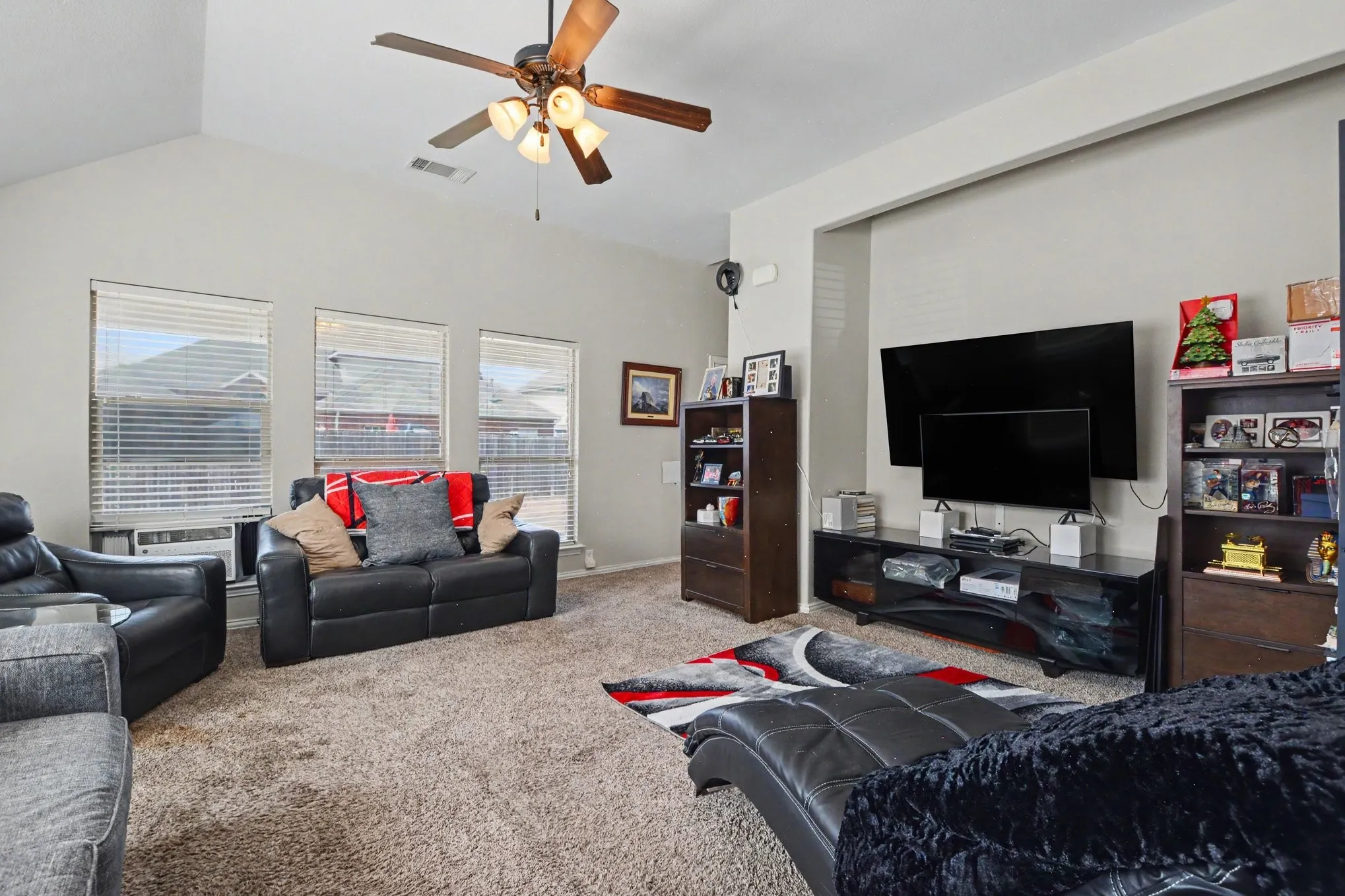Vaulted ceilings, three large windows with blinds, and a ceiling fan with integrated lighting