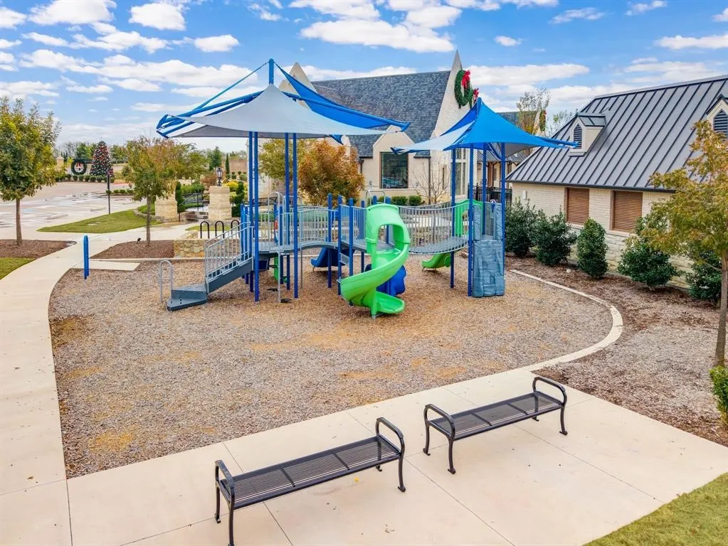 Playground area featuring multi-level structures with slides and stairs, shaded canopies, and two metal benches
