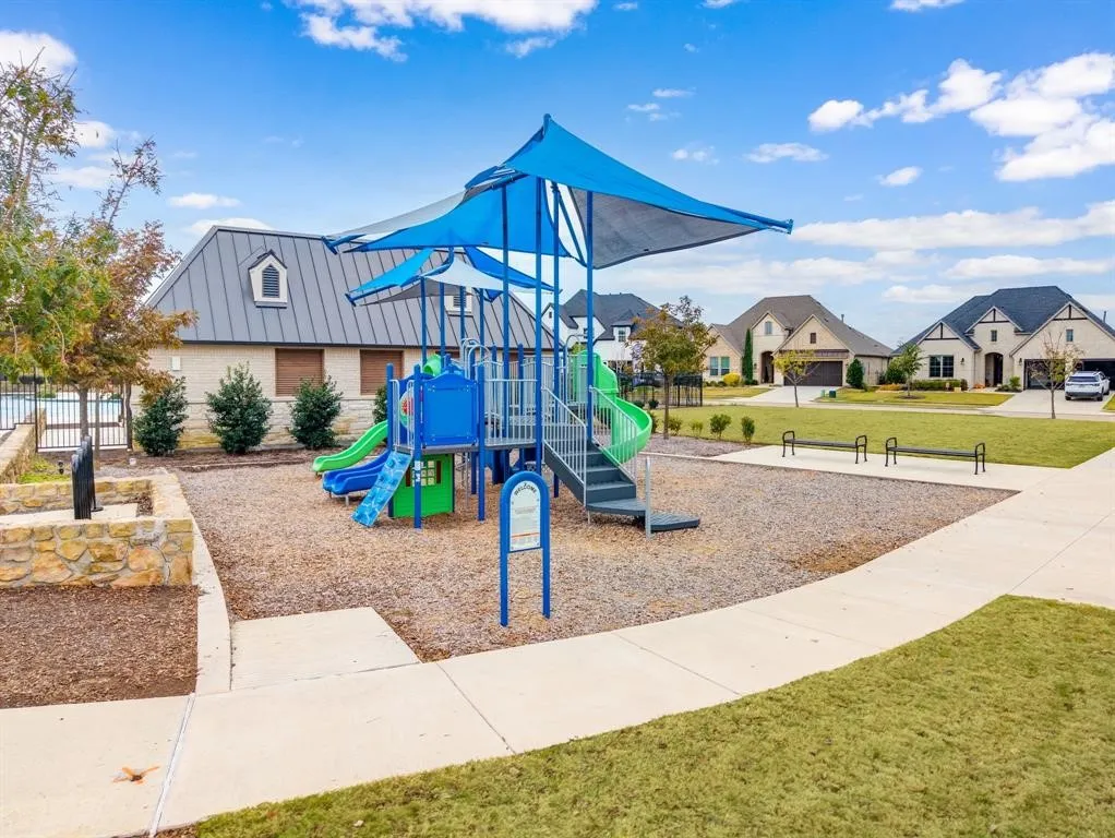 Community playground with a blue shade canopy, integrated slides, and climbing structures
