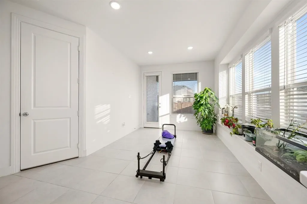 Recessed lighting illuminates a spacious room featuring large format tile flooring