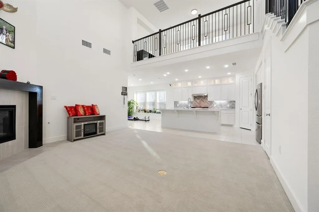 Two-story living area with a fireplace featuring a dark wood mantel and light tile surround