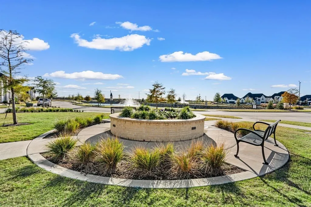 Circular planter with brick surround, decorative plantings, and paved walkway