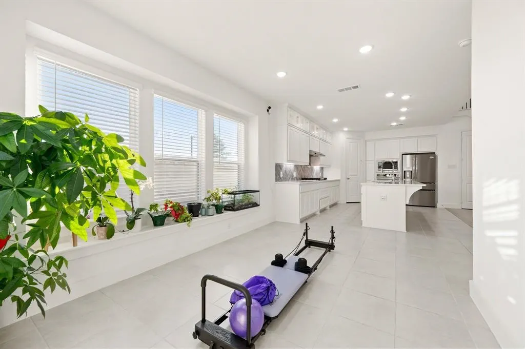 Open-concept living space featuring expansive windows, recessed lighting, a modern kitchen island, stainless steel appliances, and sleek tiled flooring