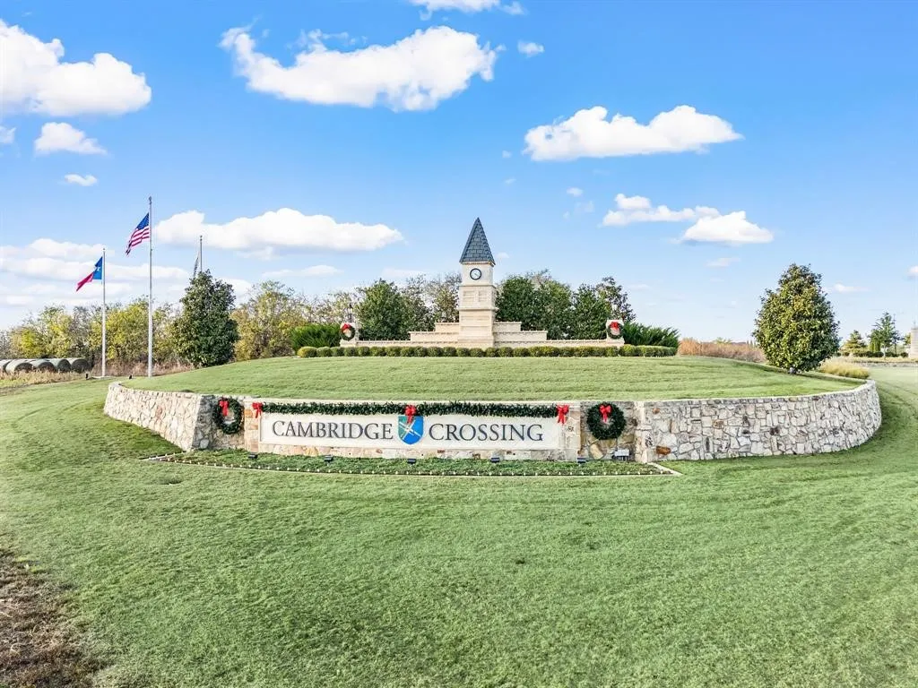 Cambridge Crossing entrance monument featuring a stone-clad wall, manicured landscaping, and a central clock tower with a steeple