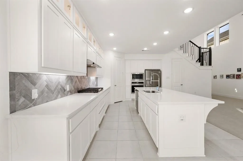 Open-concept kitchen with white cabinetry, stainless steel appliances, and a central island