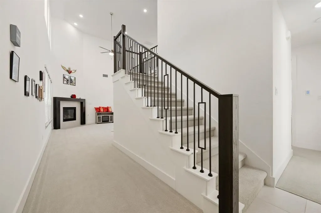 Staircase with contemporary black iron balusters, white risers, and carpeted treads
