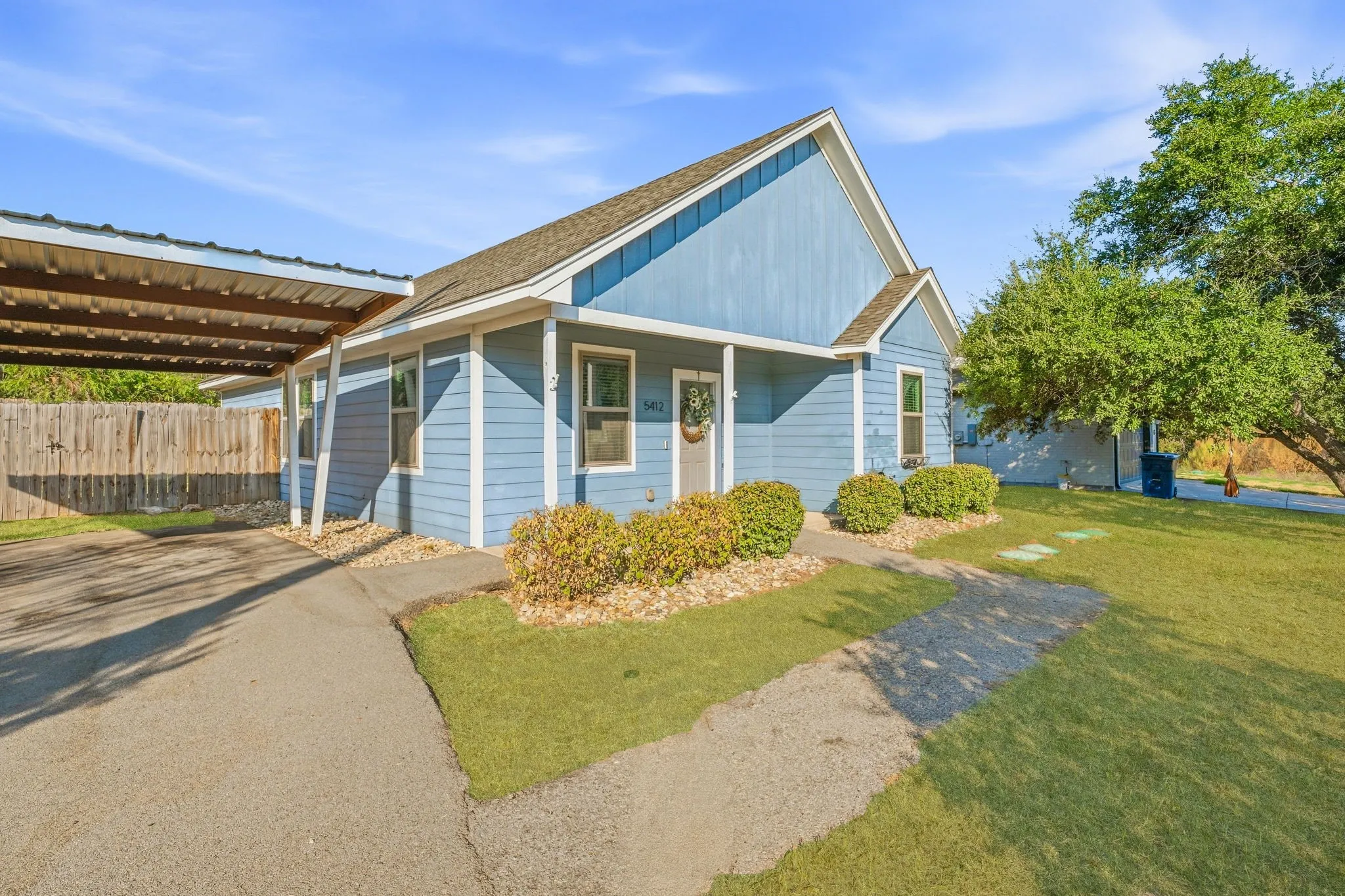 Property exterior featuring blue siding, a covered carport, an asphalt driveway, and a front porch