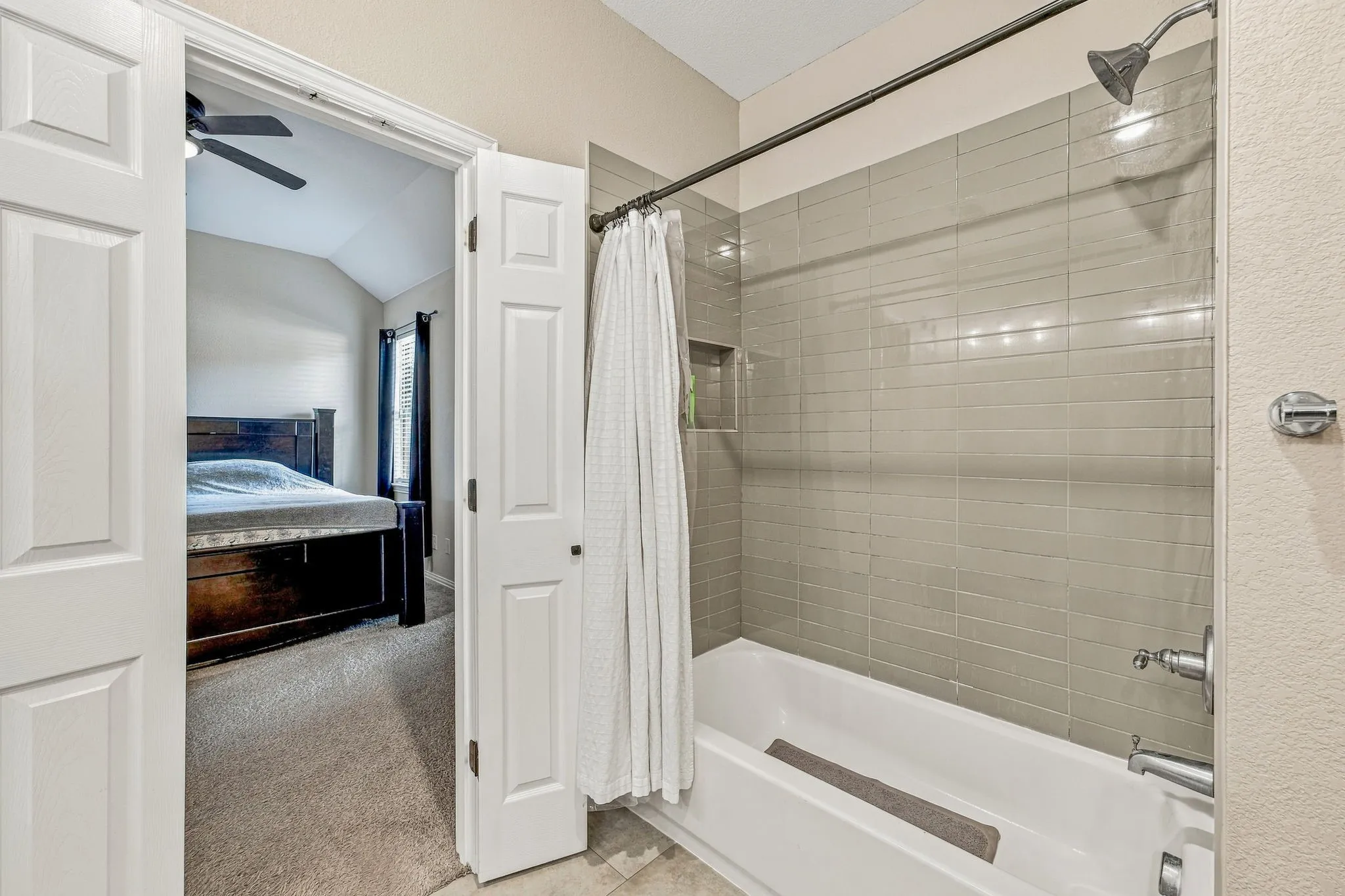 Bathtub with subway tile surround, integrated shower niche, and brushed nickel fixtures
