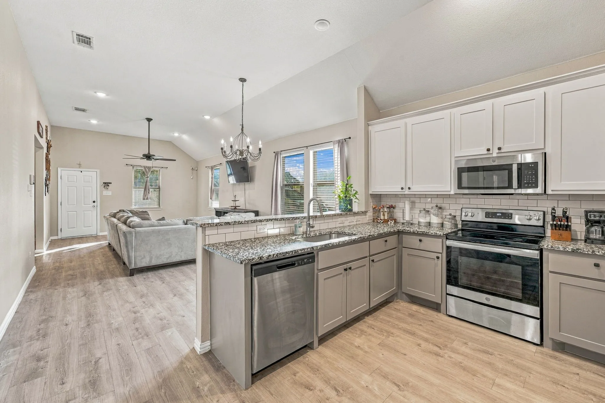 Open-concept kitchen with stainless steel appliances, granite countertops, and subway tile backsplash