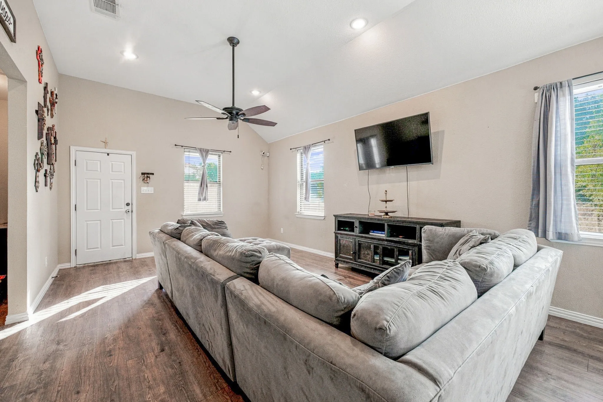 Vaulted ceiling with a ceiling fan, wood-finish flooring, recessed lighting, and multiple windows
