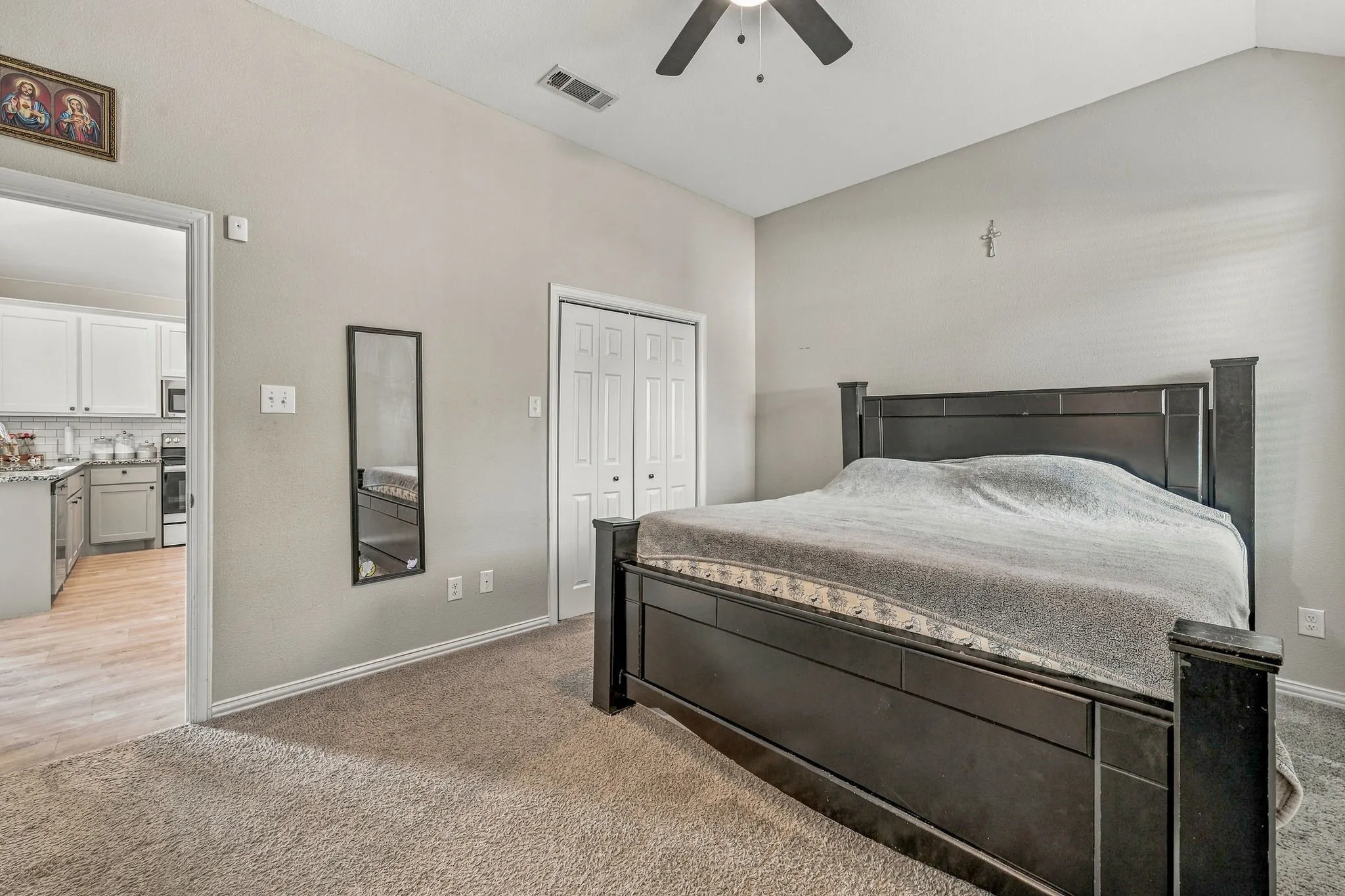 Vaulted ceiling with an attached ceiling fan, carpet flooring, bi-fold closet doors, and light gray wall paint