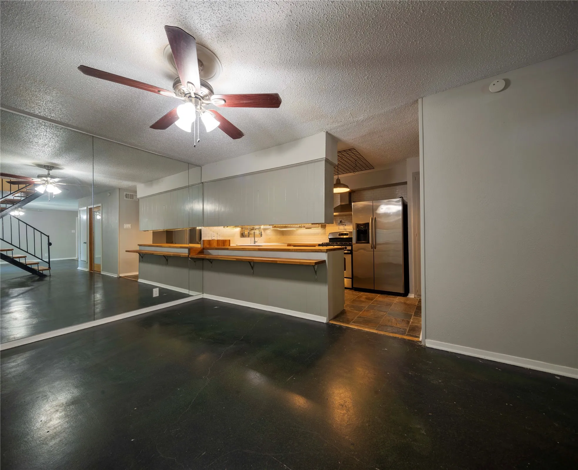 Open-concept living area featuring dark polished flooring and reflective mirrored wall panels